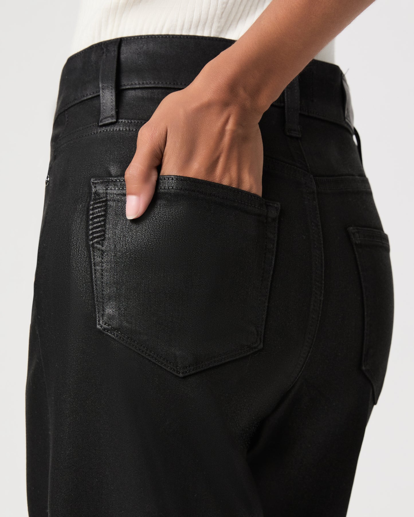 women wearing a white top paired with black jeans against a white background