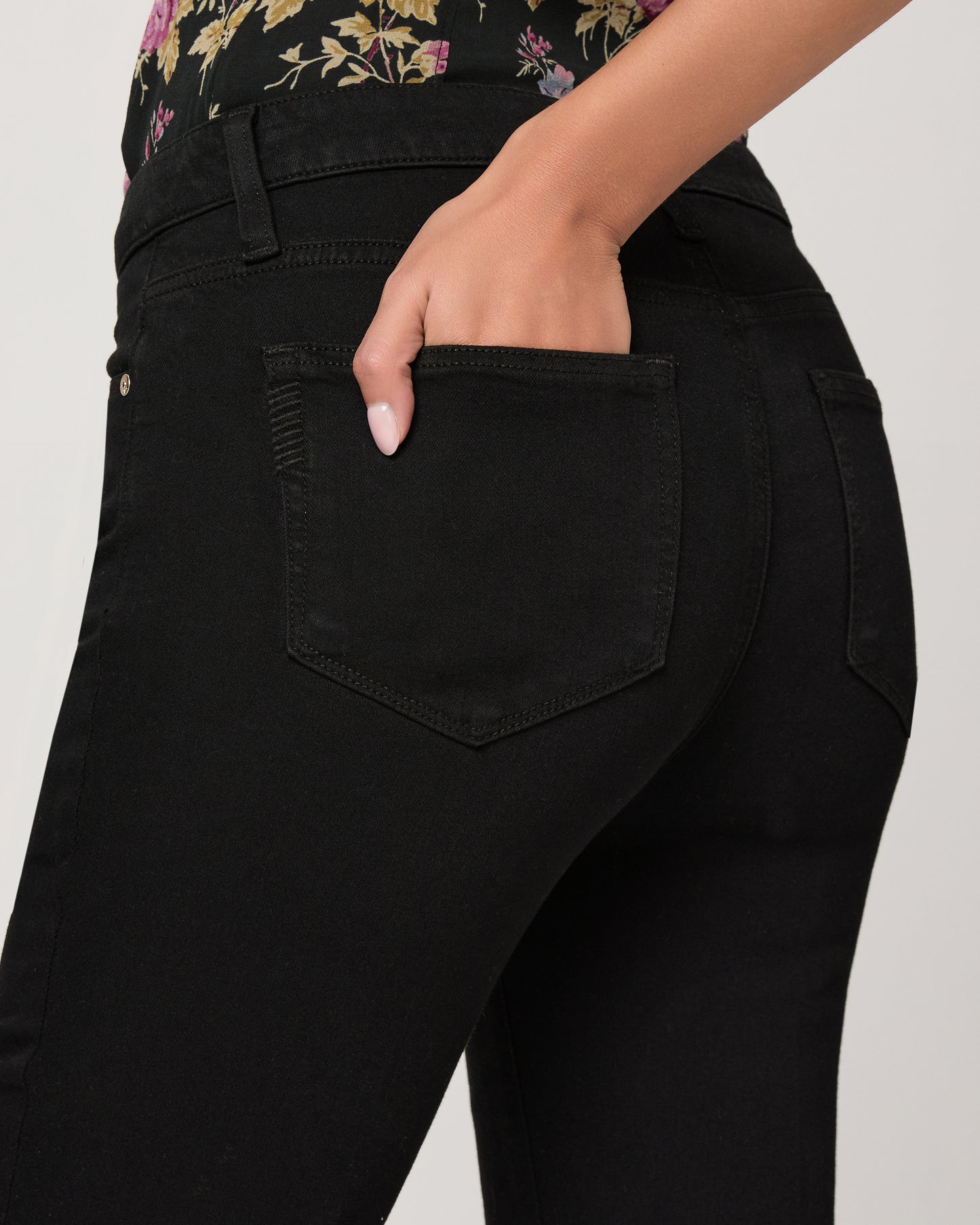 Woman wearing a floral to and black pants on a white background