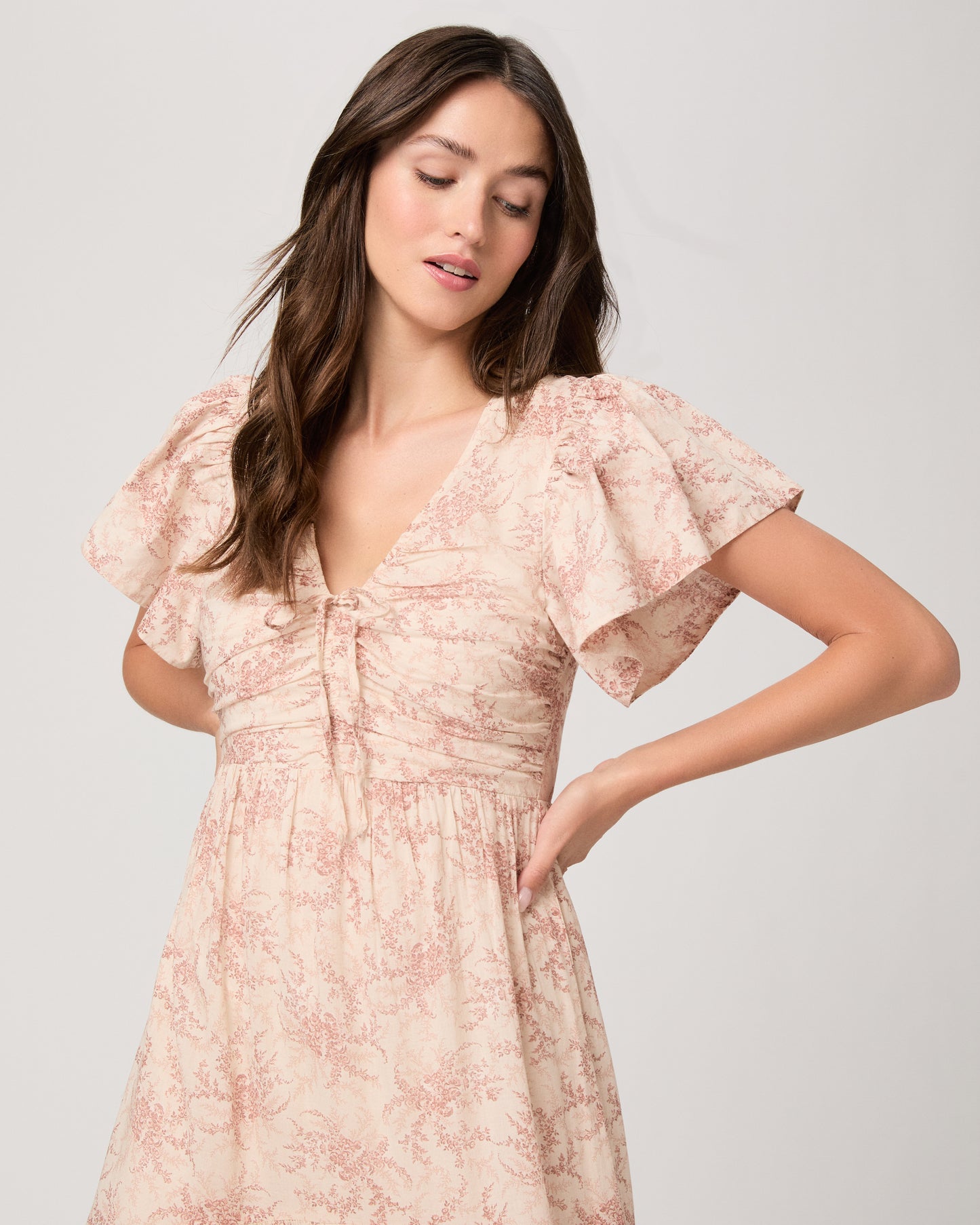 Woman wearing a long, patterned pink dress on a white background