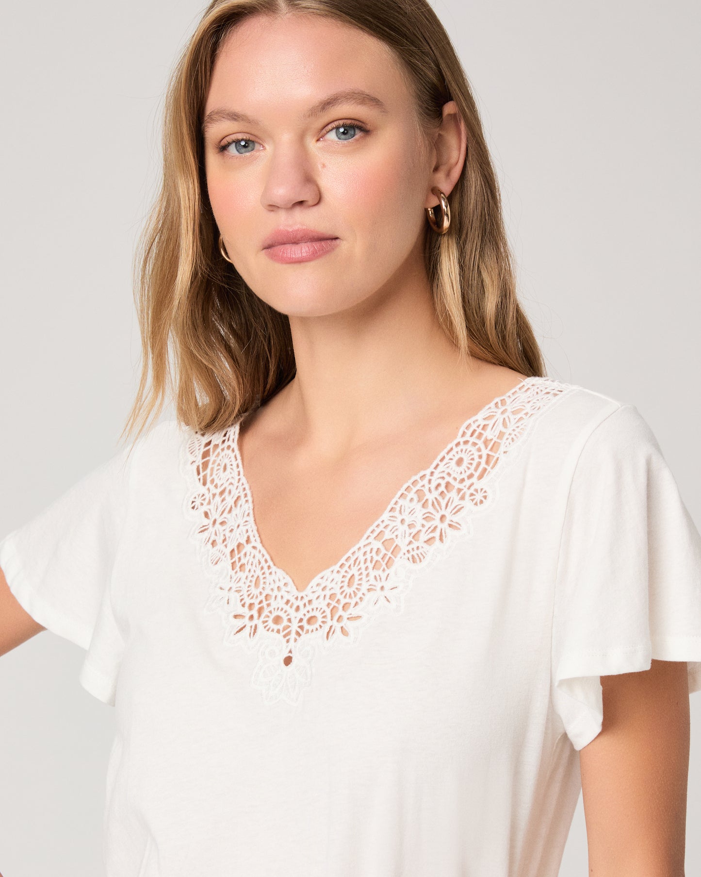 Woman wearing a white top paired with off white skirt on a white background