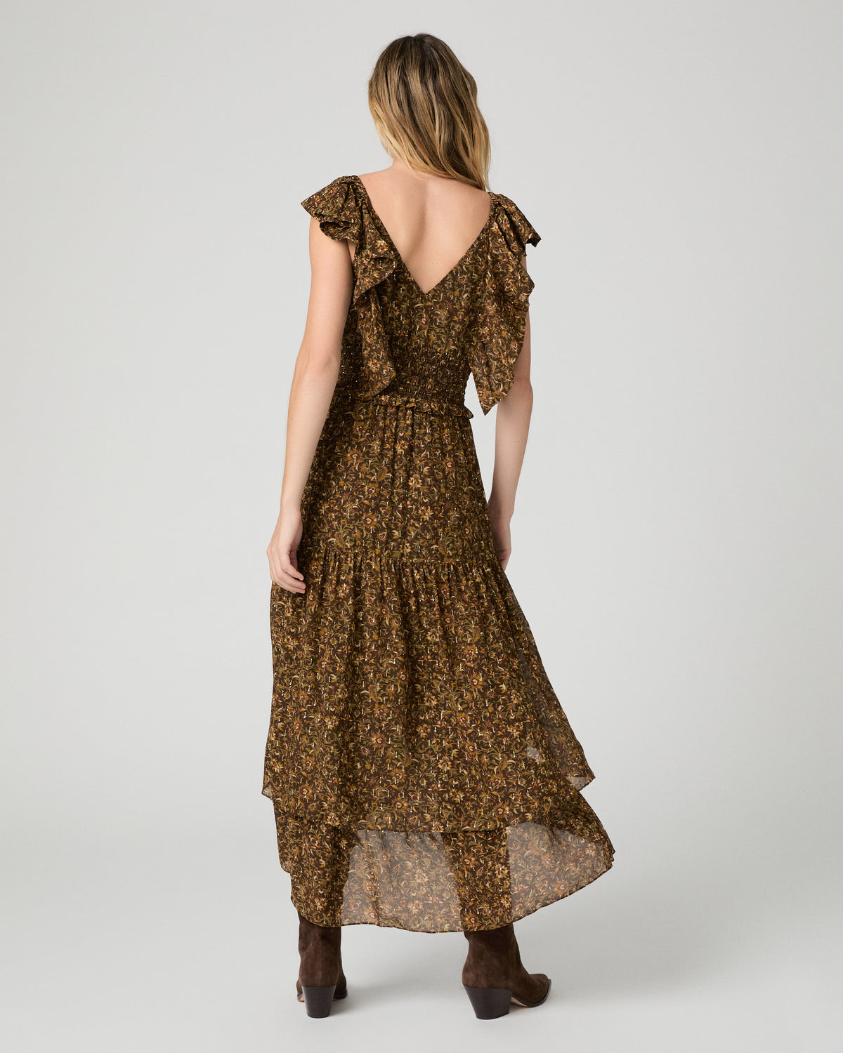 Women wearing a flower printed brown dress and paired with brown boots against a white background
