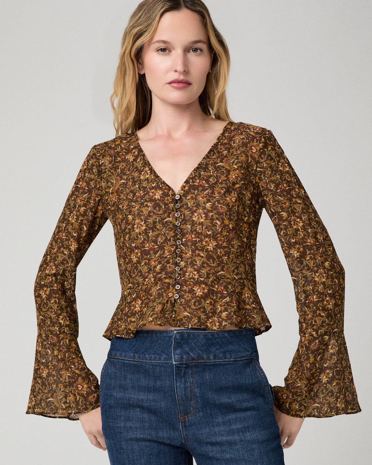 Women wearing a flower print blouse paired with blue jeans against a white background