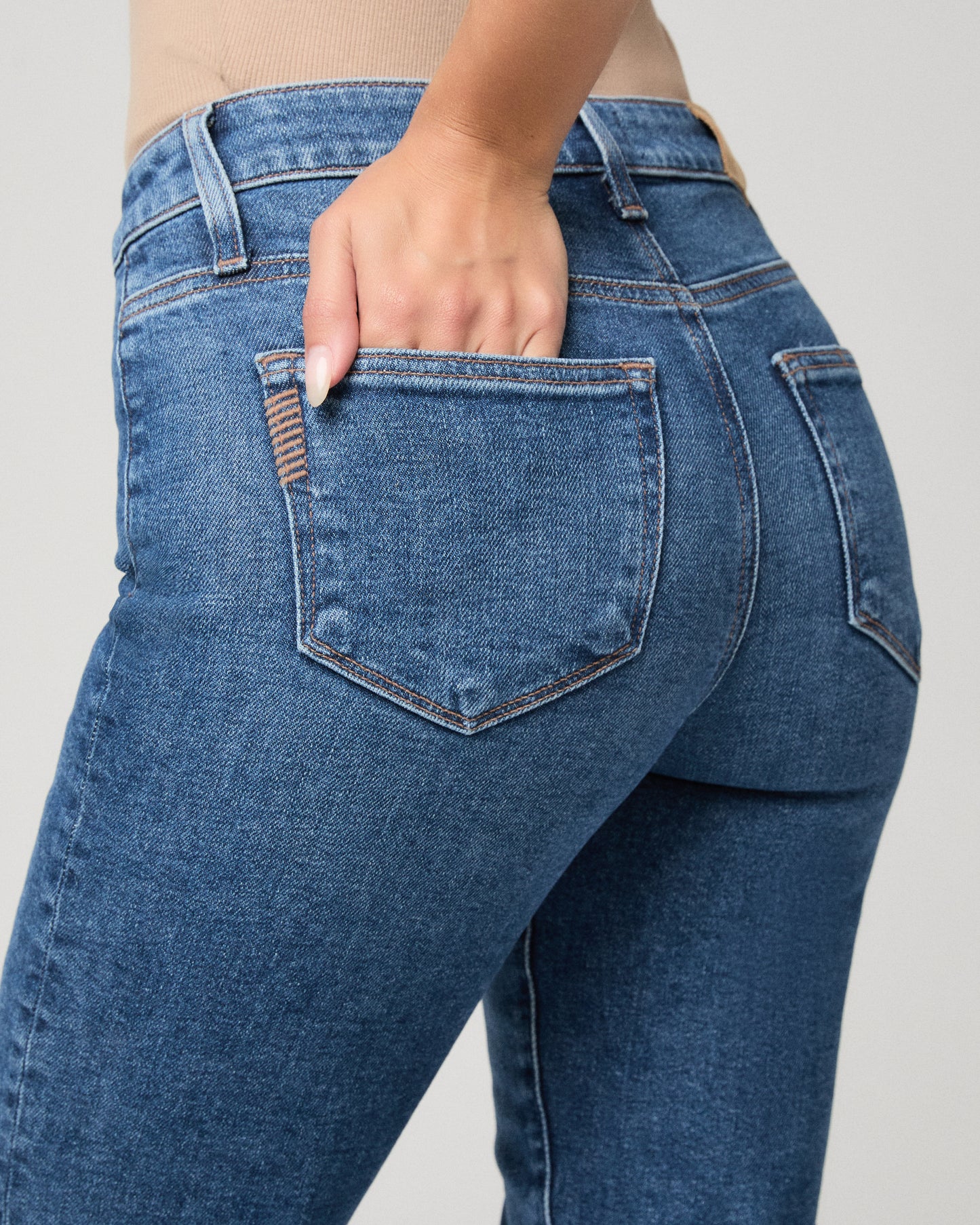 Woman in a brown jacket with blue jeans and a white background
