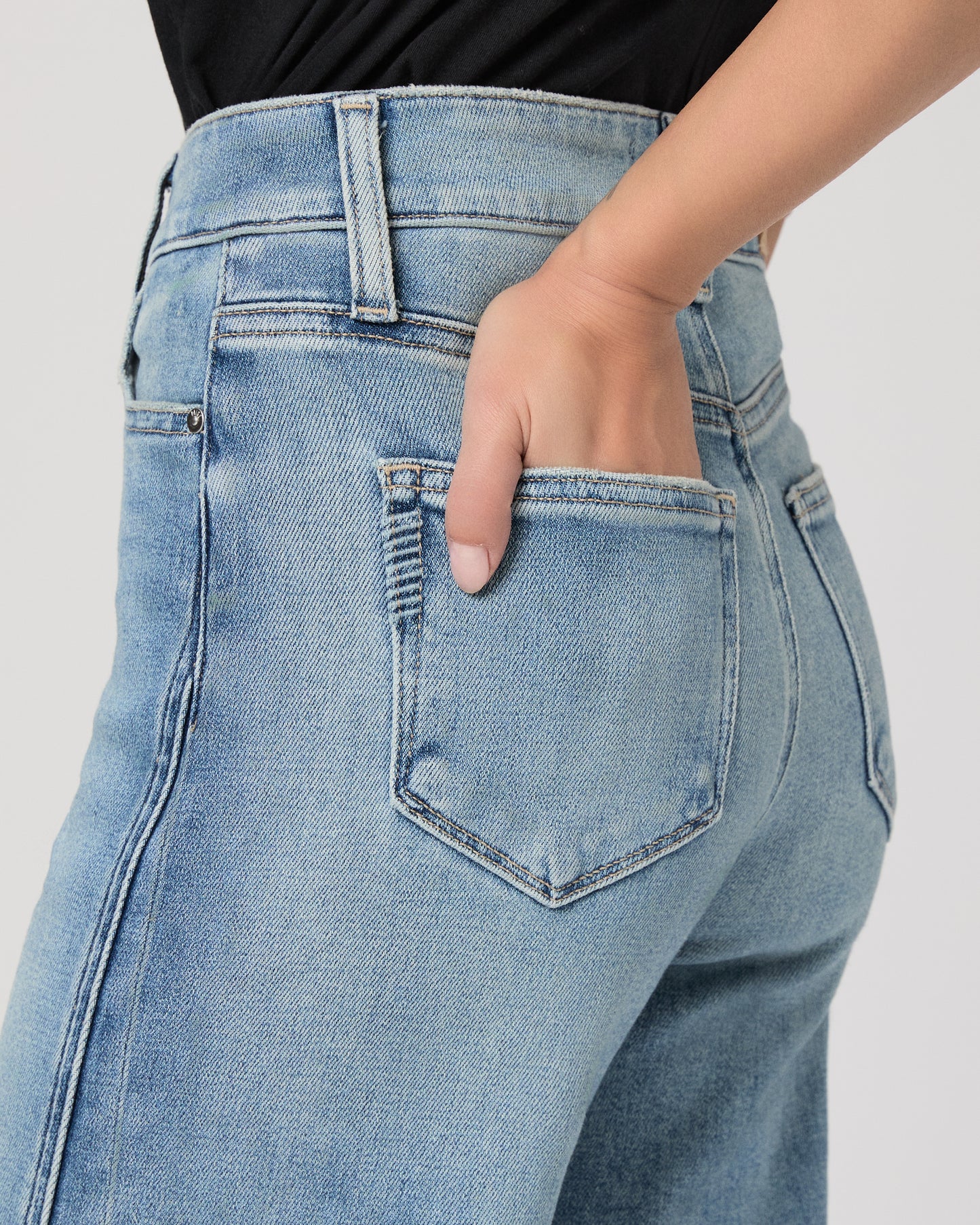Woman wearing a black top and blue jeans on a white background