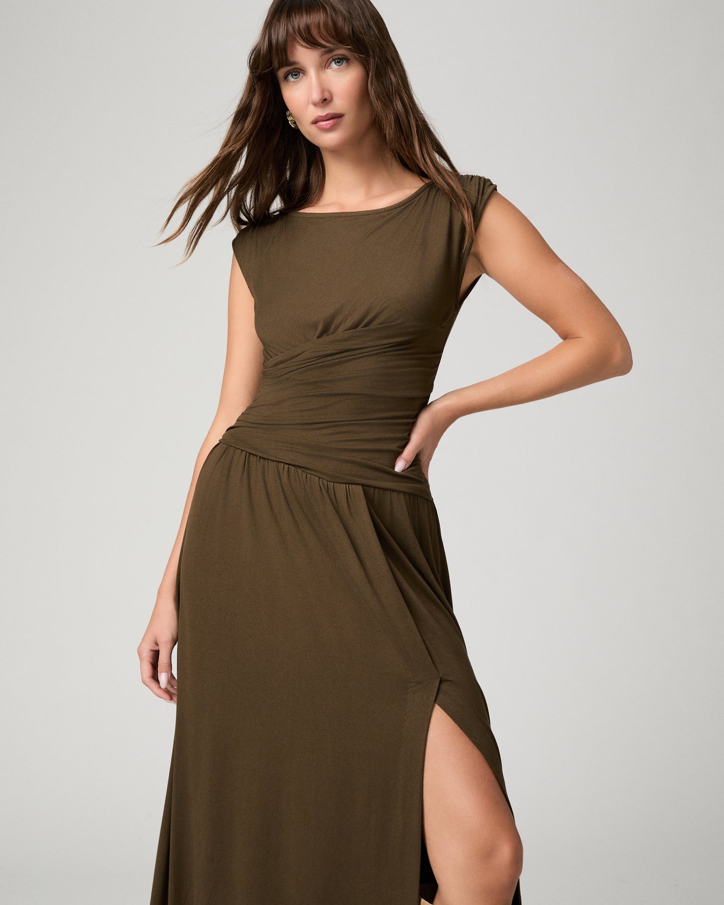 Women wearing a dark green maxi dress paired with brown boots against a white background