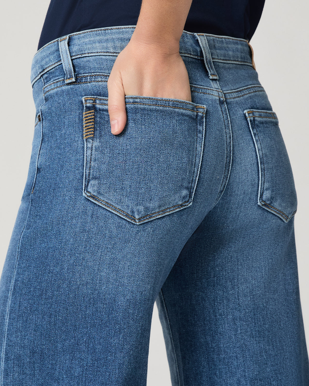 Women wearing a blue tee paired with blue jeans standing against a white background