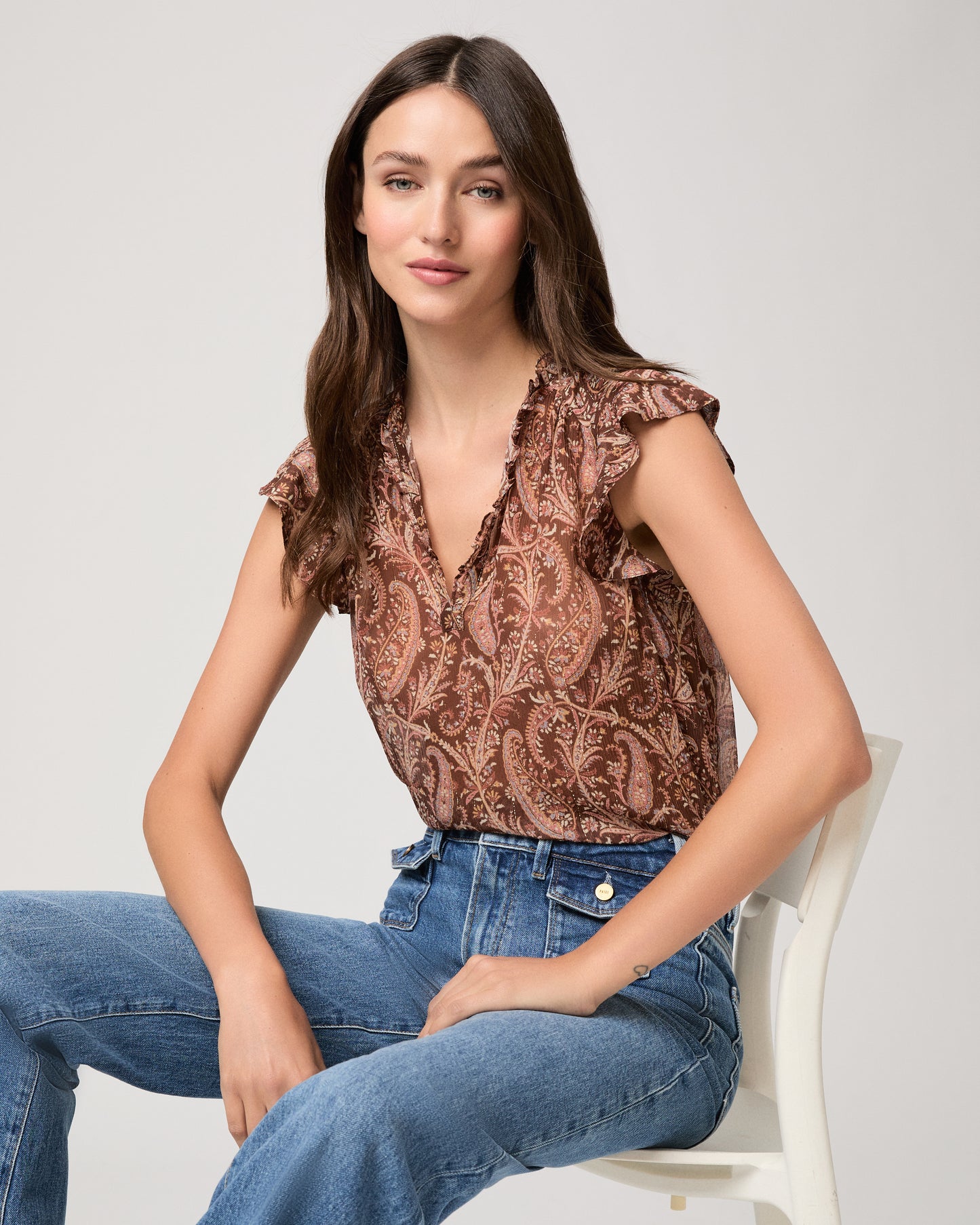 Model wearing a printed brown short sleeve top paired with medium wash denim jeans