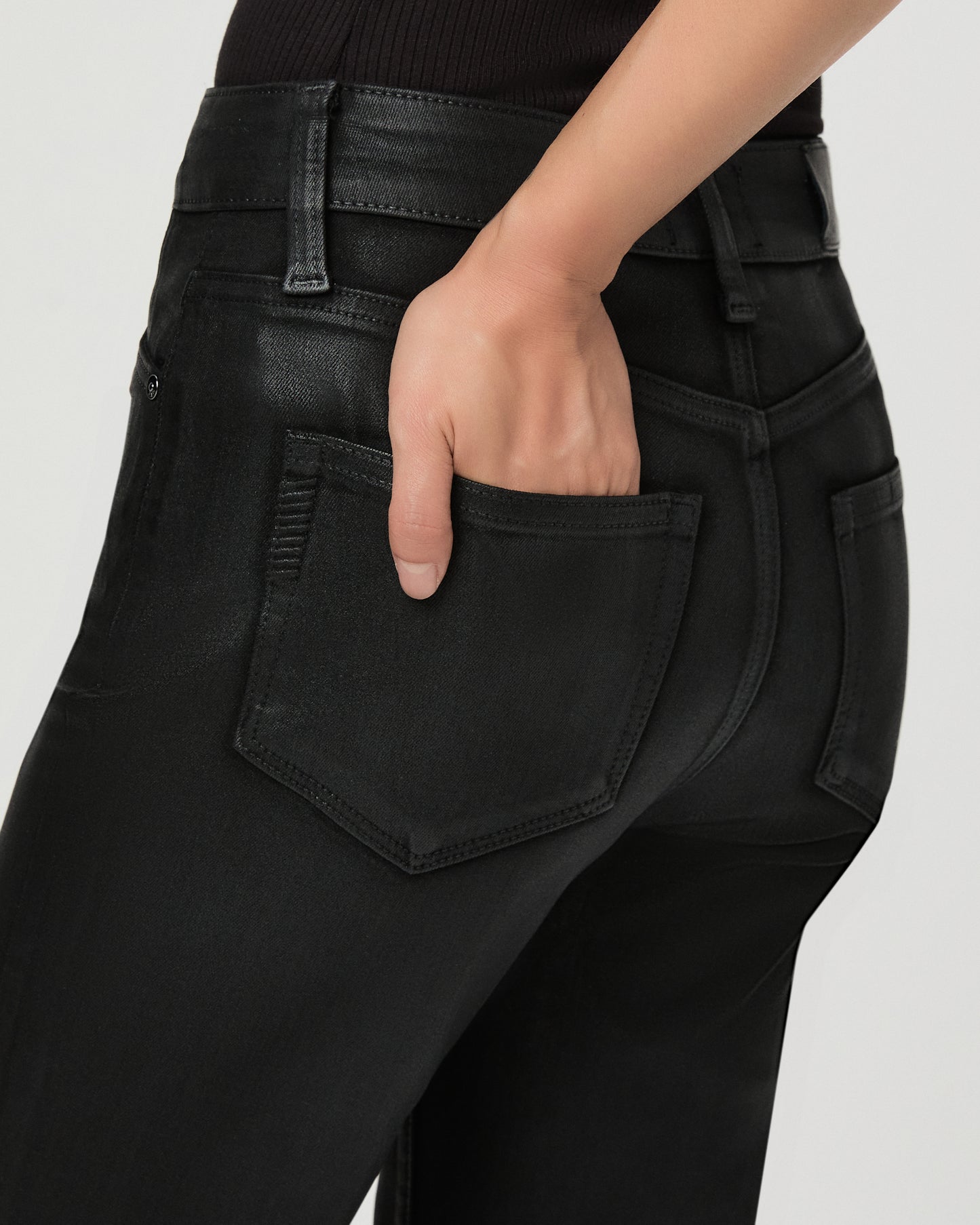 A woman modeling a black off-the-shoulder crop top and black wide-leg flare jeans against a light gray studio background.
