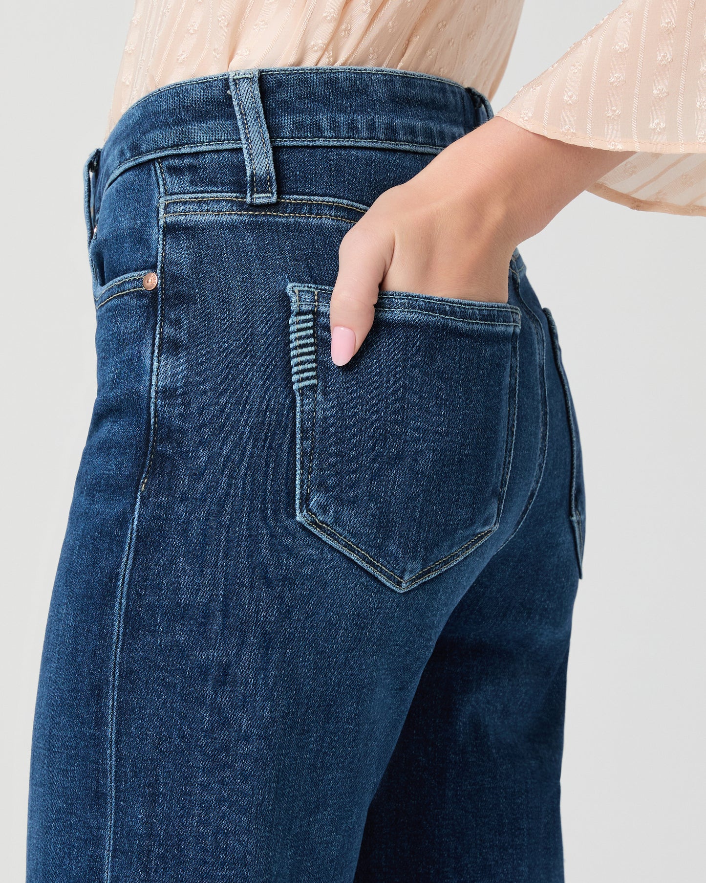 Woman wearing a beige blouse and blue jeans on a white background