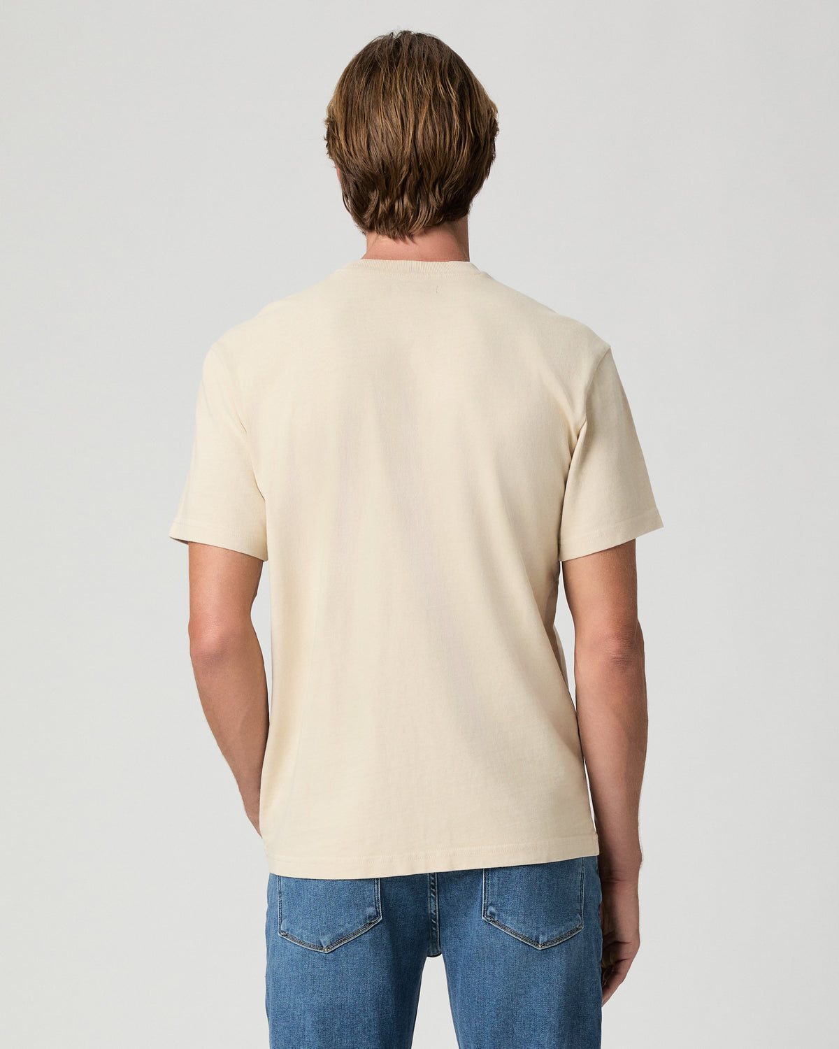 Back view of model wearing the Serano Boxy Tee in Pale Antler with medium-wash jeans