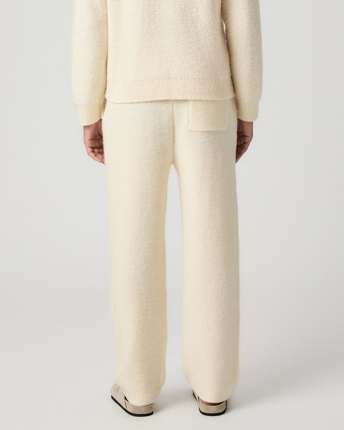 Back view from the waist down of the Willits Sweater Pant in Marfil, worn with tan suede shoes