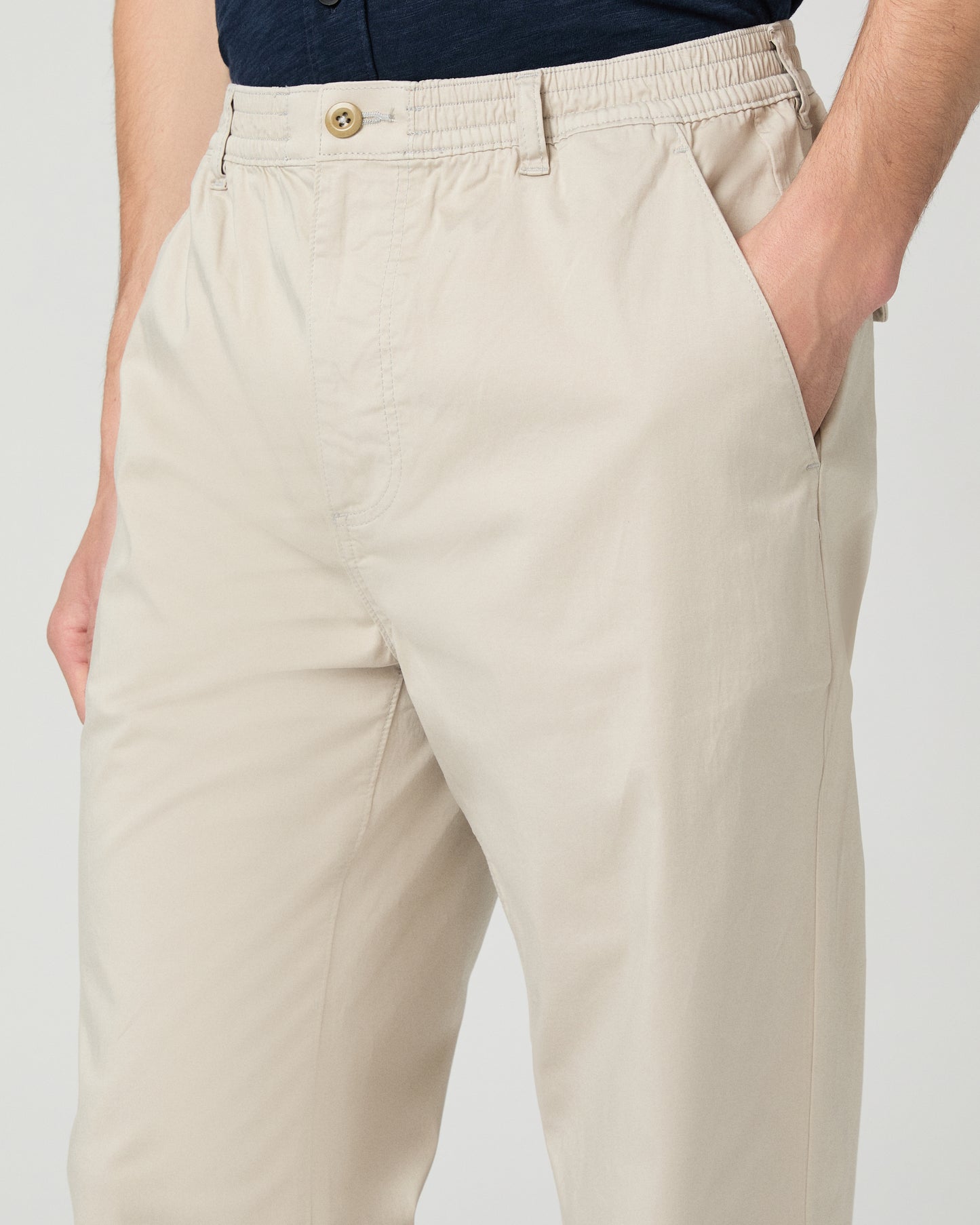 Man wearing a navy shirt and beige pants on a white background