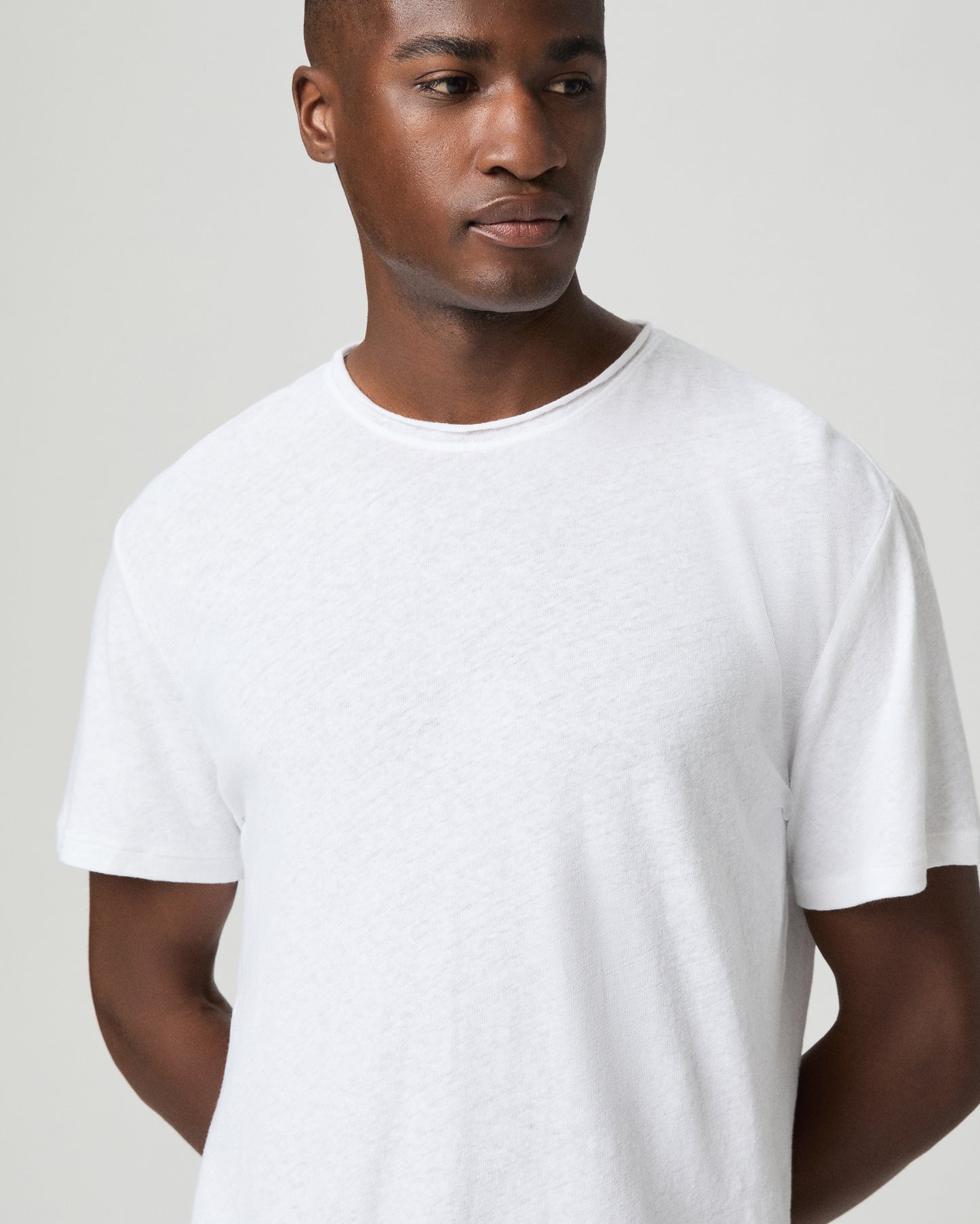 Man wearing a plain white t-shirt and light blue jeans against a white background