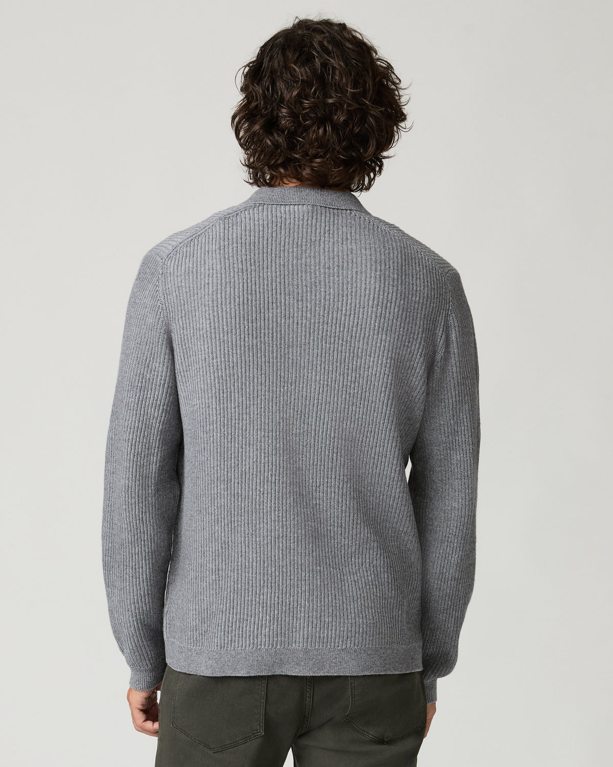 Back view of a man wearing the heather gray ribbed-knit Spokane Cardigan, showing the point collar and vertical rib-knit texture, paired with dark olive trousers.