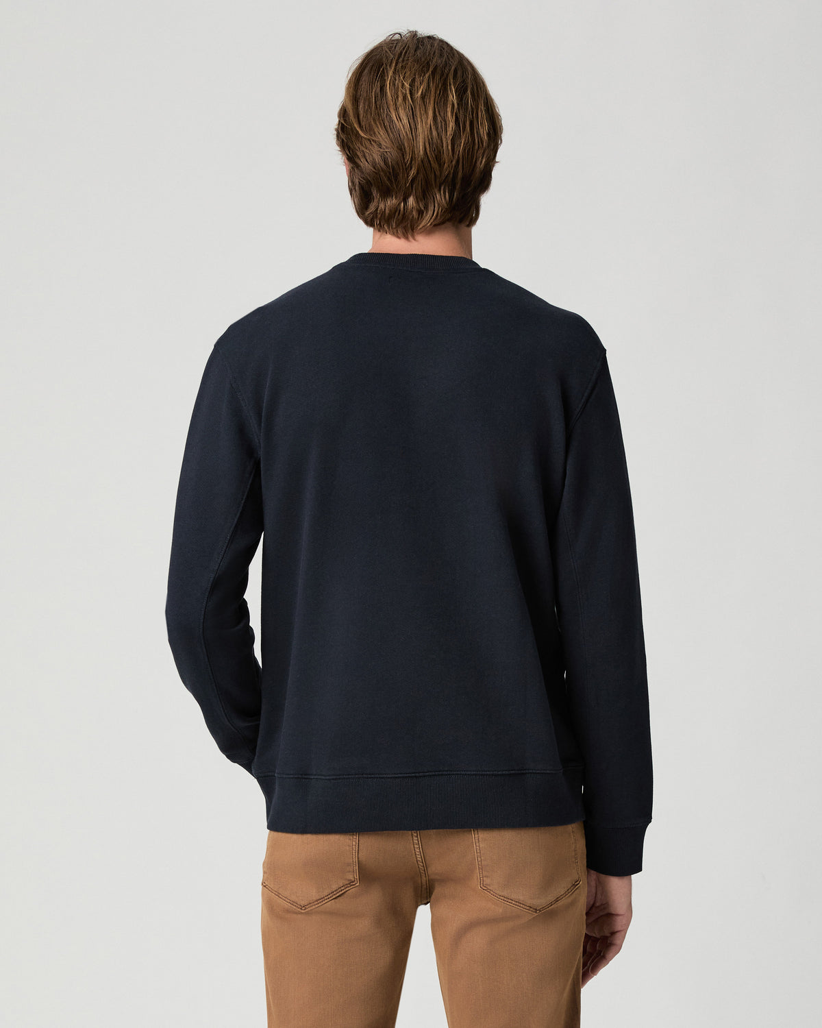 Back view of model wearing the Devlin Crewneck in Deep Anchor with tan pants