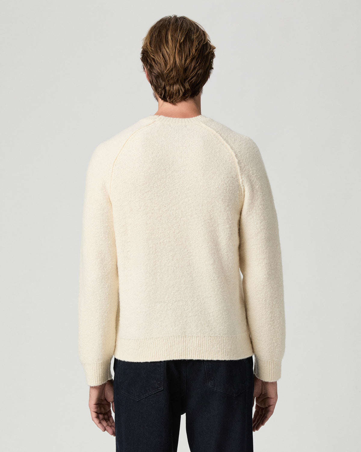 Back view of model wearing the Hightower Crewneck Sweater in Marfil with dark jeans