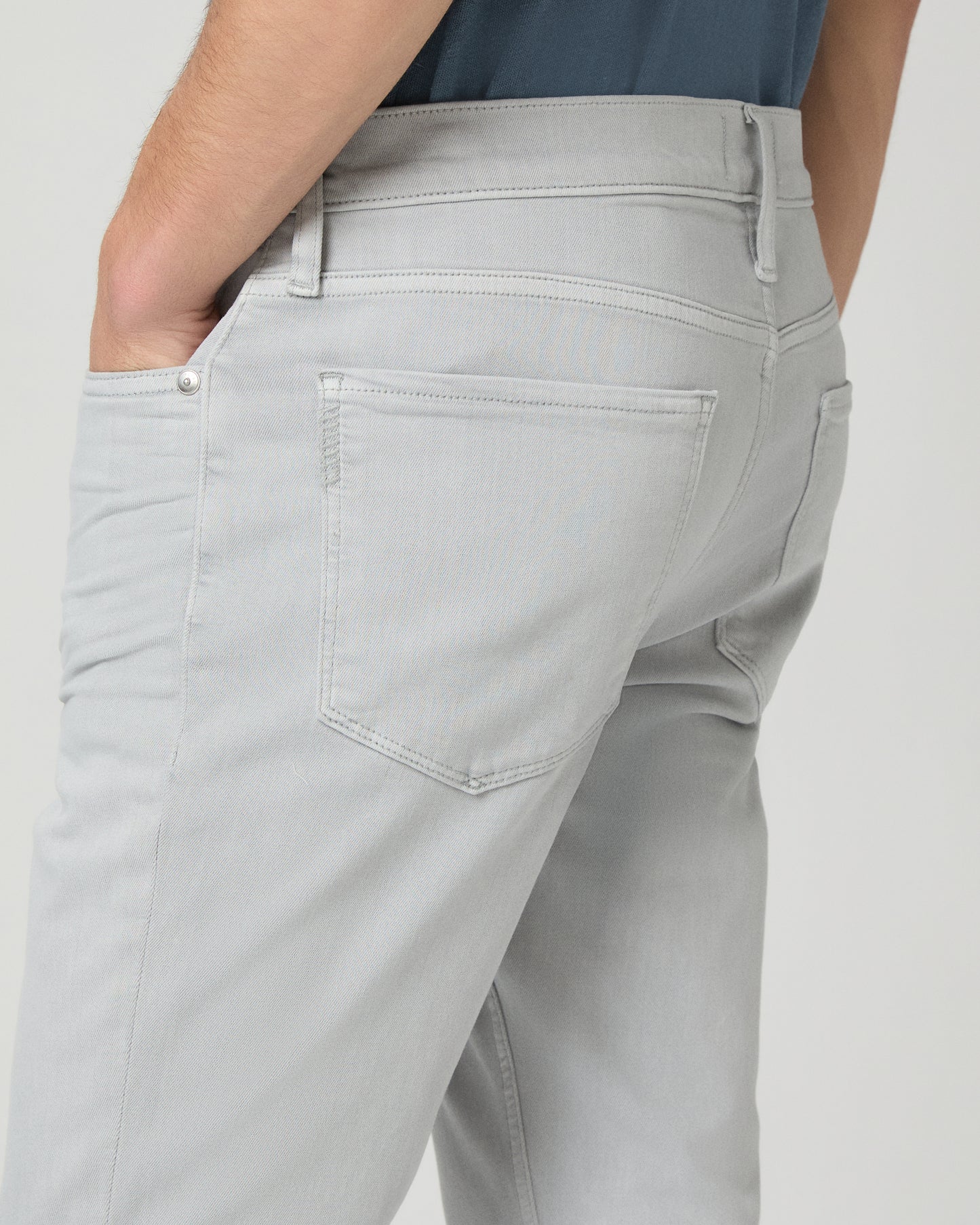 Man wearing a blue t-shirt and gray pants on a white background