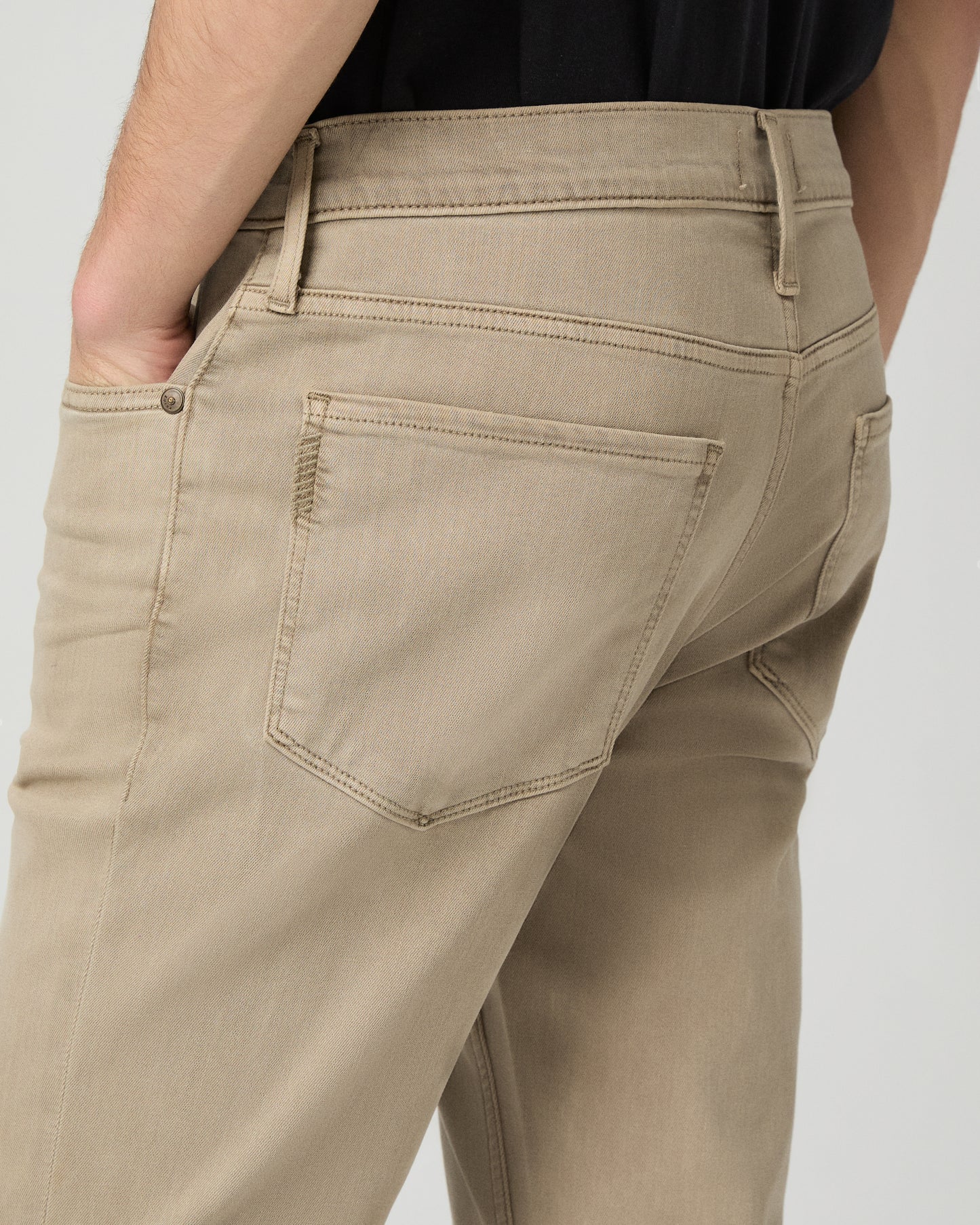 Man wearing a black t-shirt, beige pants, and white shoes on a white background