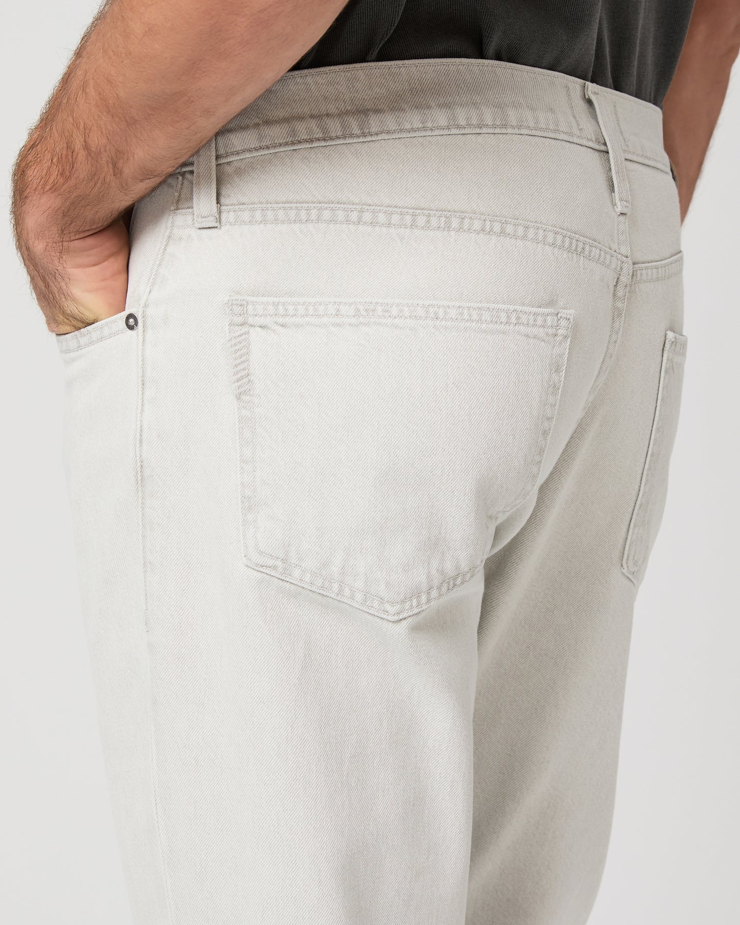 Man wearing a gray t-shirt and white pants on a white background