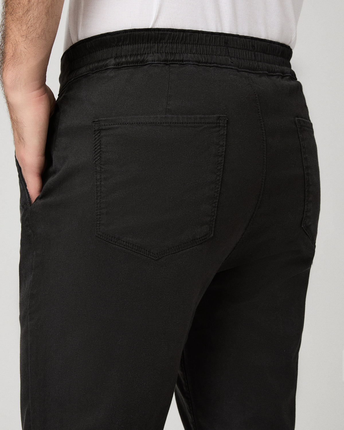 Man wearing grey shirt and black pants against a white background