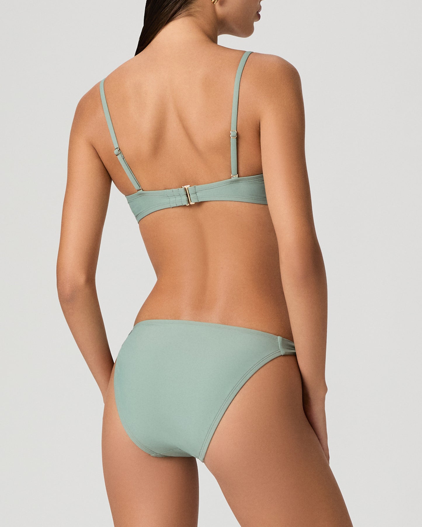 Woman wearing a light green bikini set on a white background