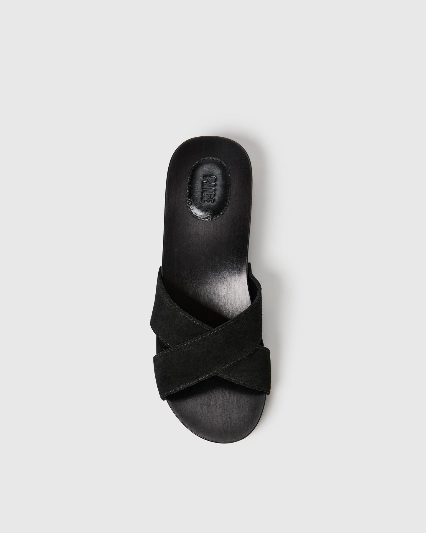 Black sandal with criss-cross strap design on a light gray background