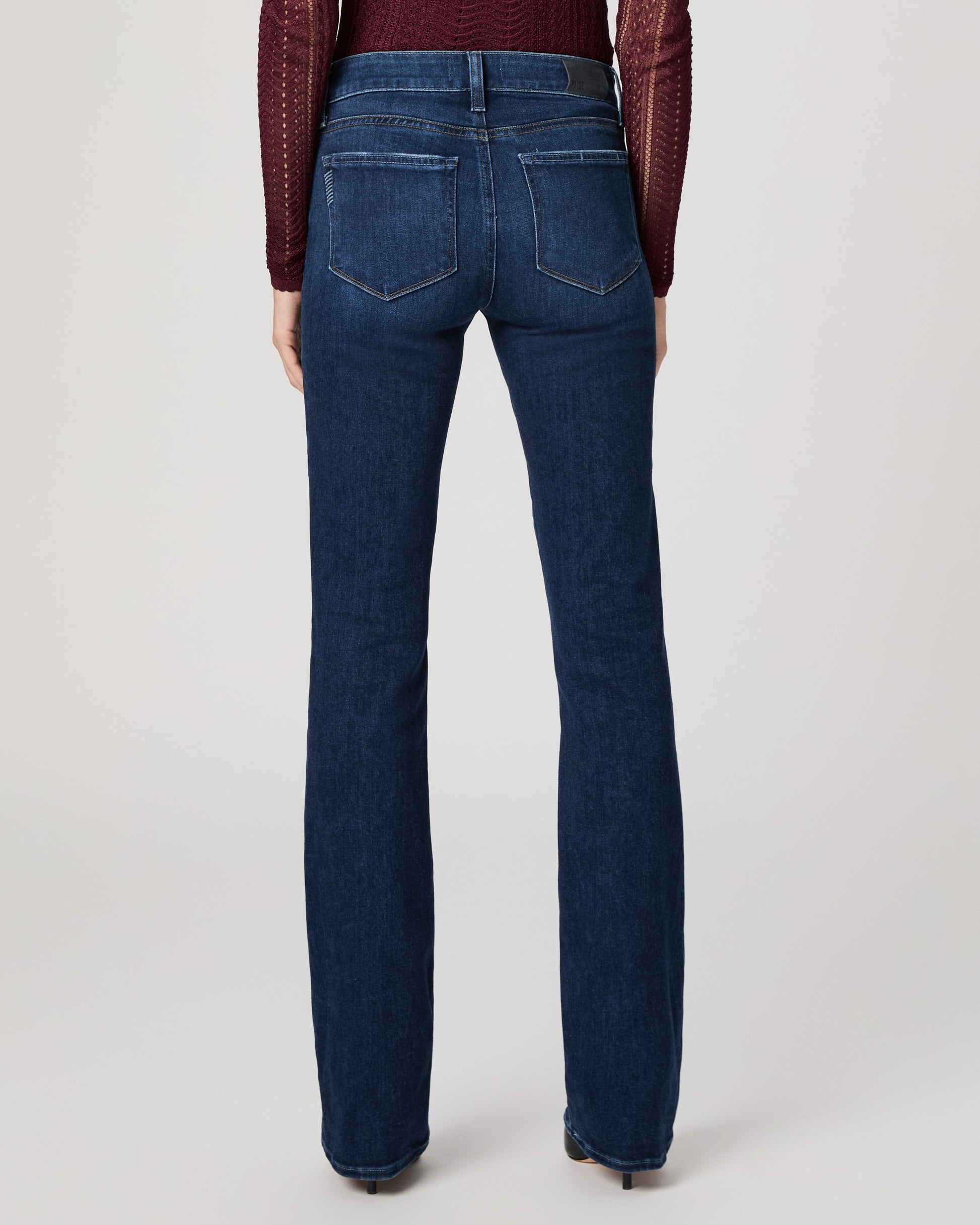 Woman wearing a burgundy top and blue jeans on a white background