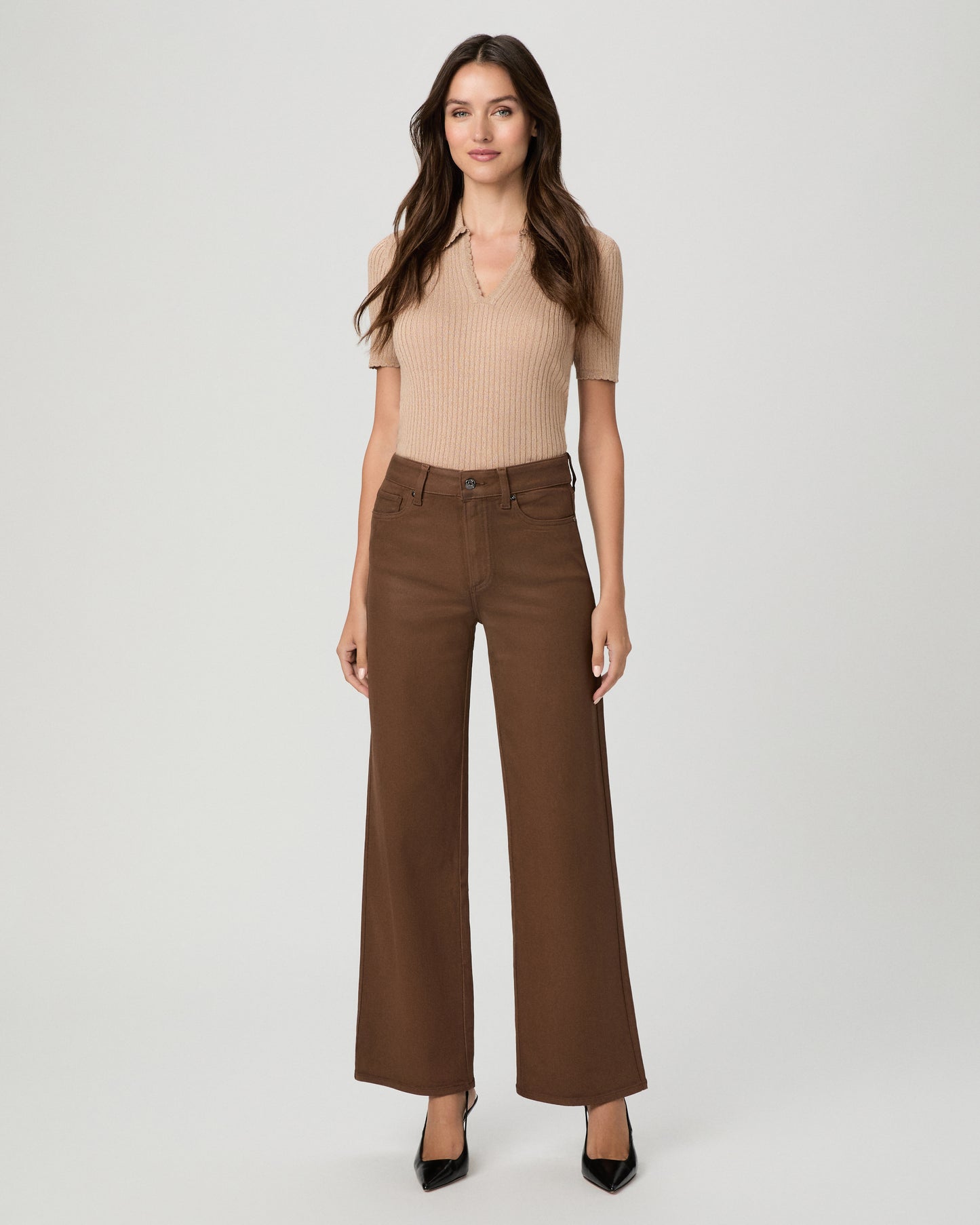 A woman modeling a beige ribbed short-sleeve top and brown wide-leg pants against a light gray studio background.