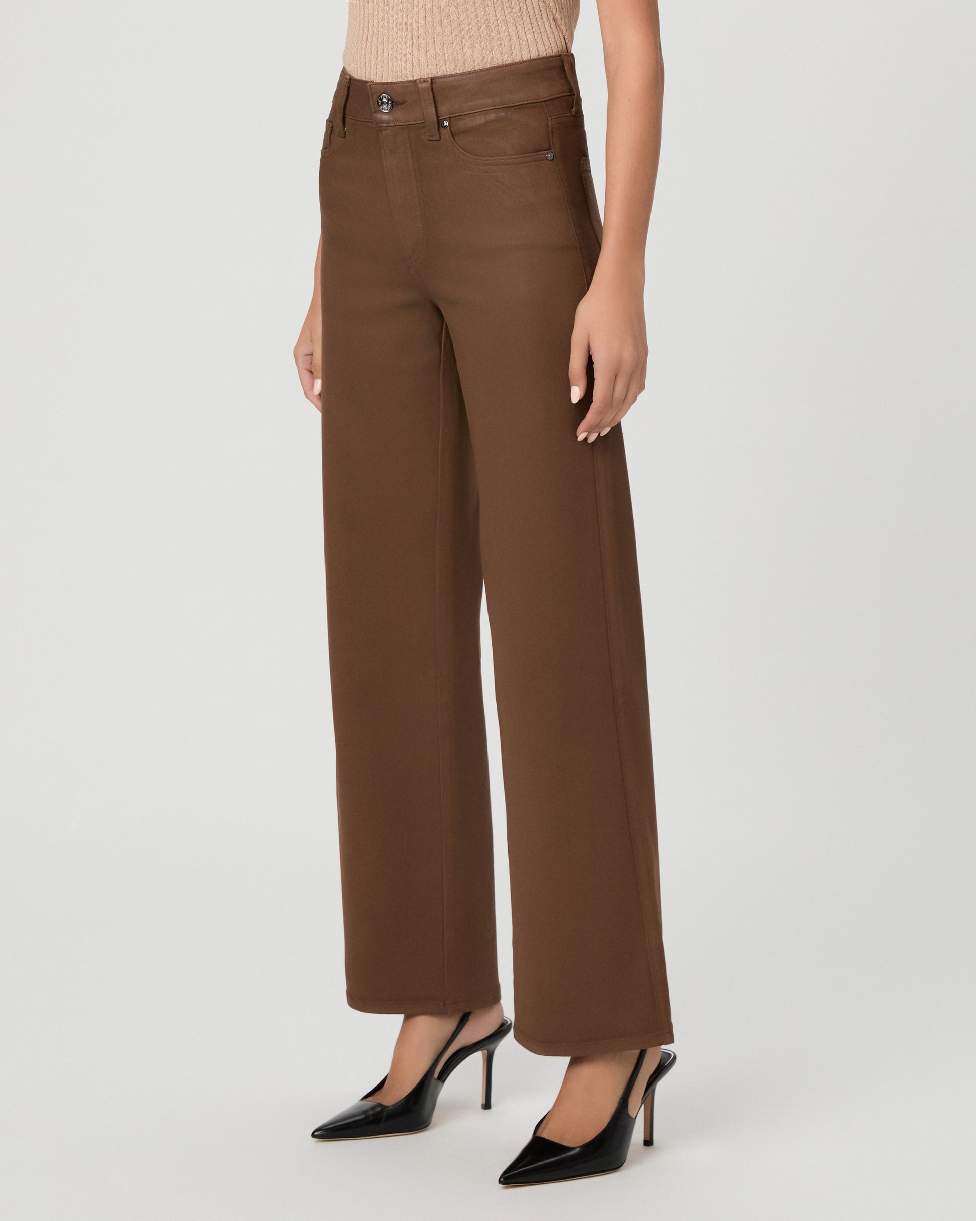 A woman modeling a beige ribbed short-sleeve top and brown wide-leg pants against a light gray studio background.