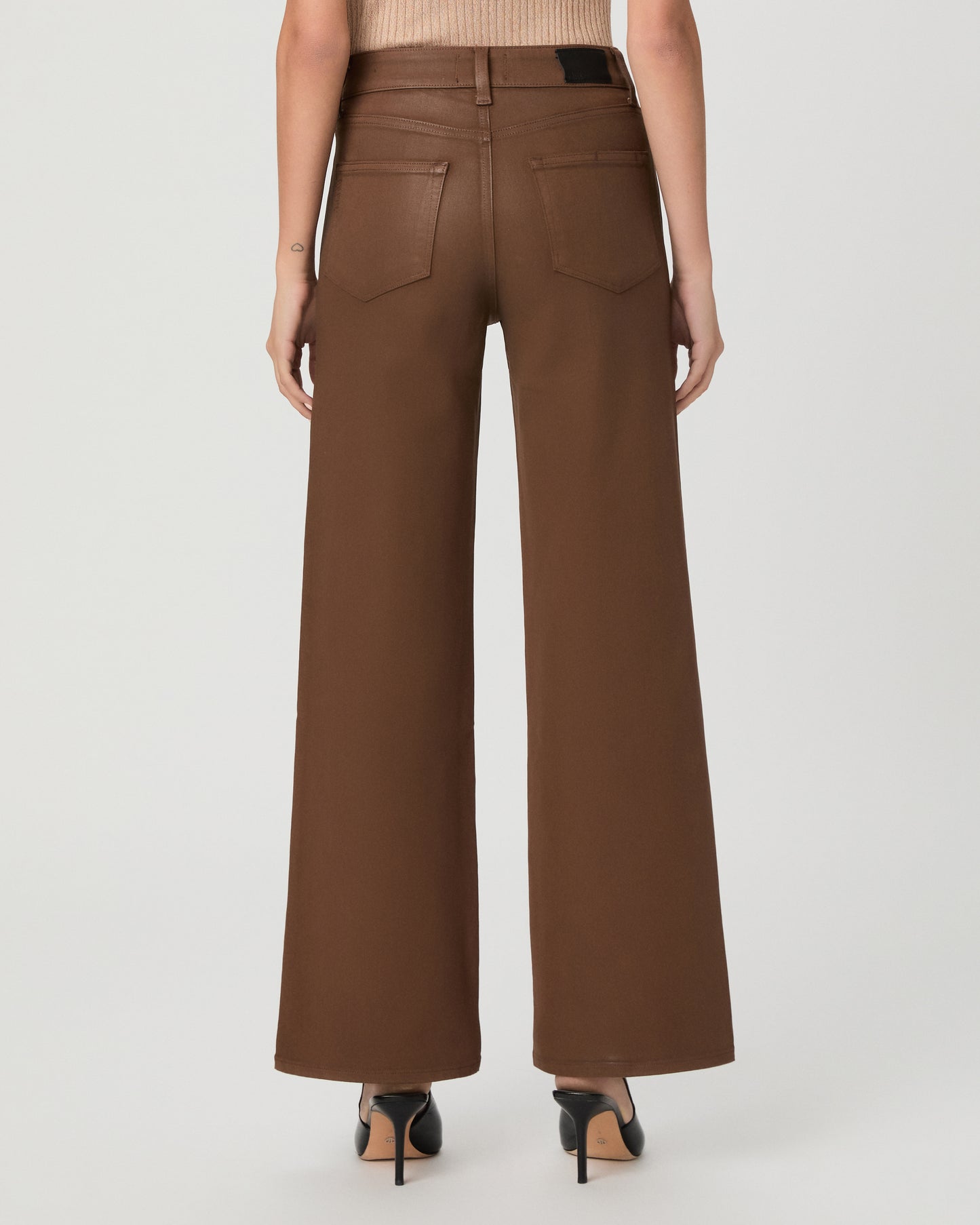 A woman modeling a beige ribbed short-sleeve top and brown wide-leg pants against a light gray studio background.