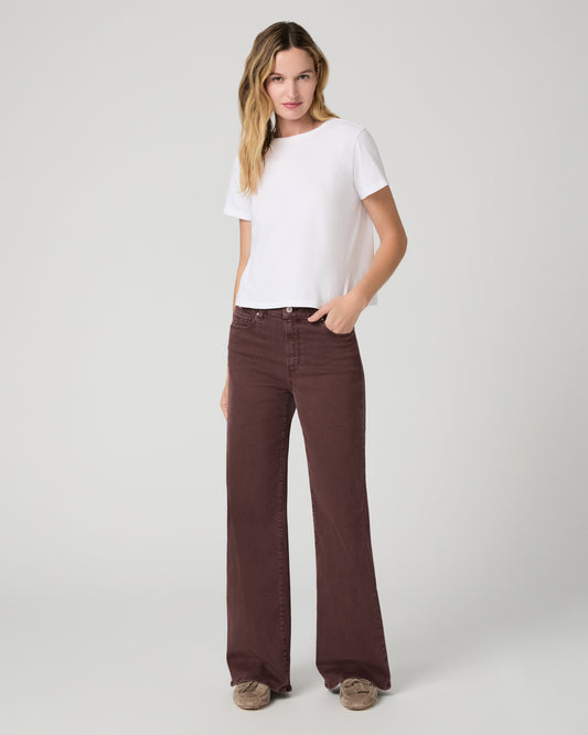 Women wearing a white top paired with burgundy jean and brown flats against a white background