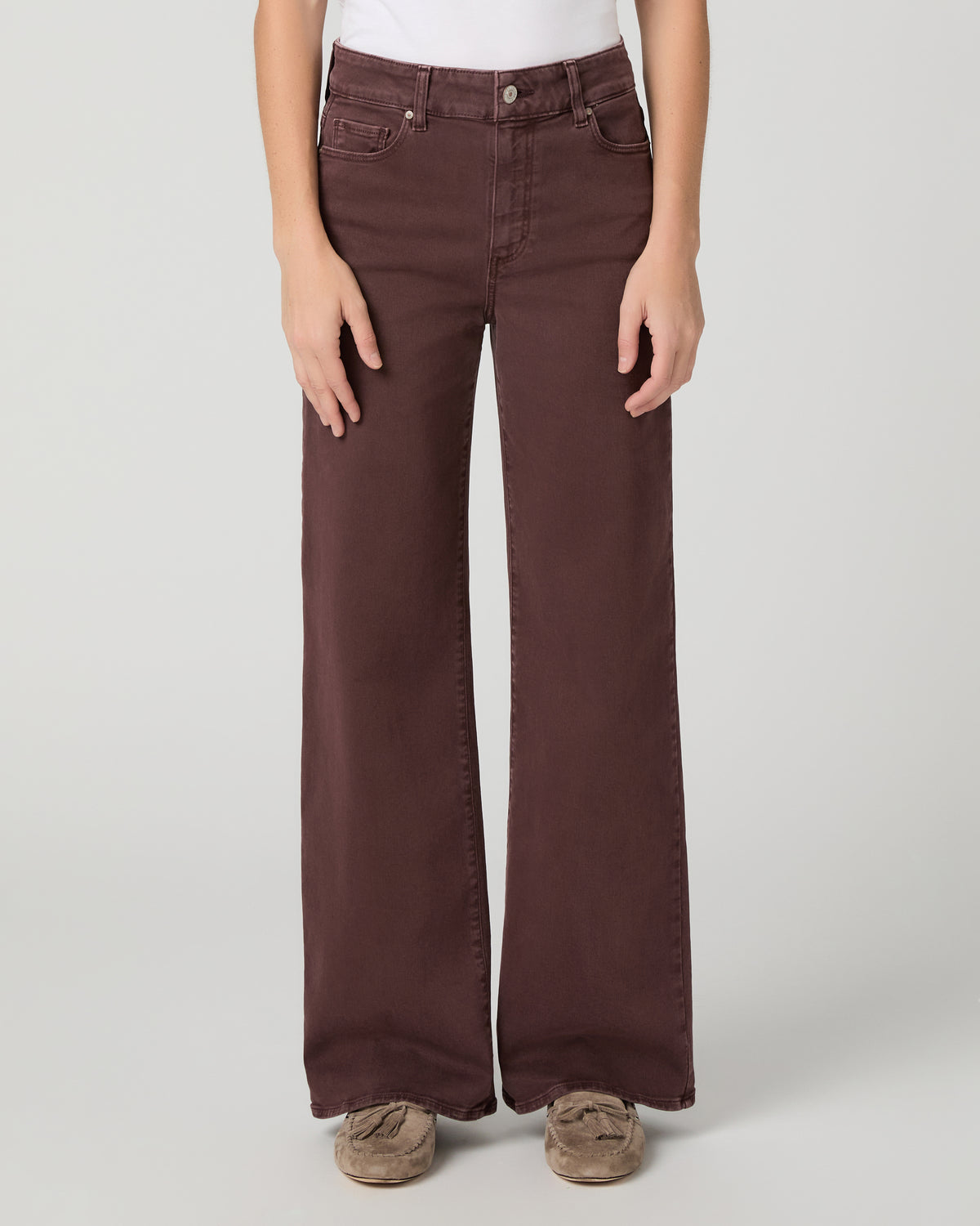 Women wearing a white top paired with burgundy jean and brown flats against a white background