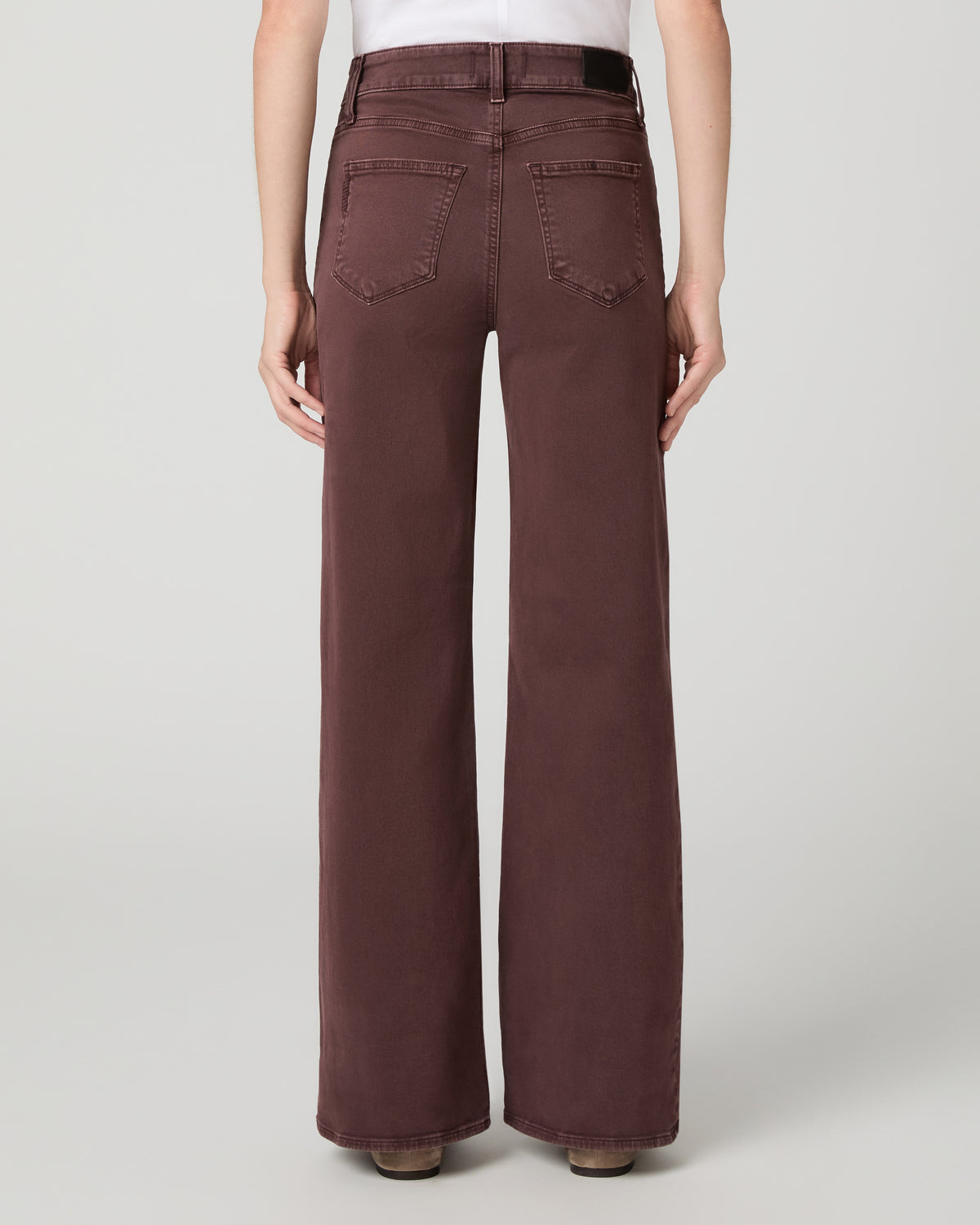 Women wearing a white top paired with burgundy jean and brown flats against a white background