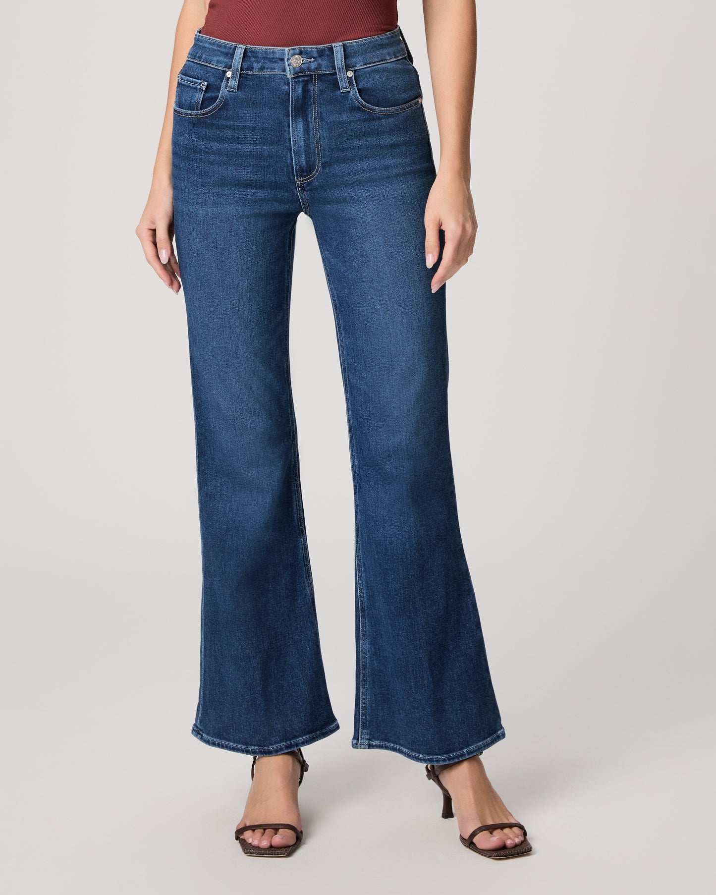 Person wearing blue flared jeans on a plain background