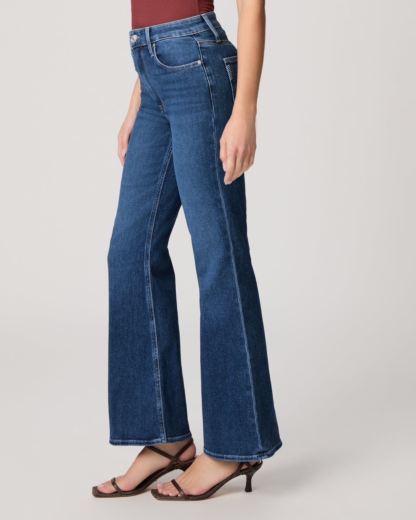 Person wearing blue jeans on a plain background