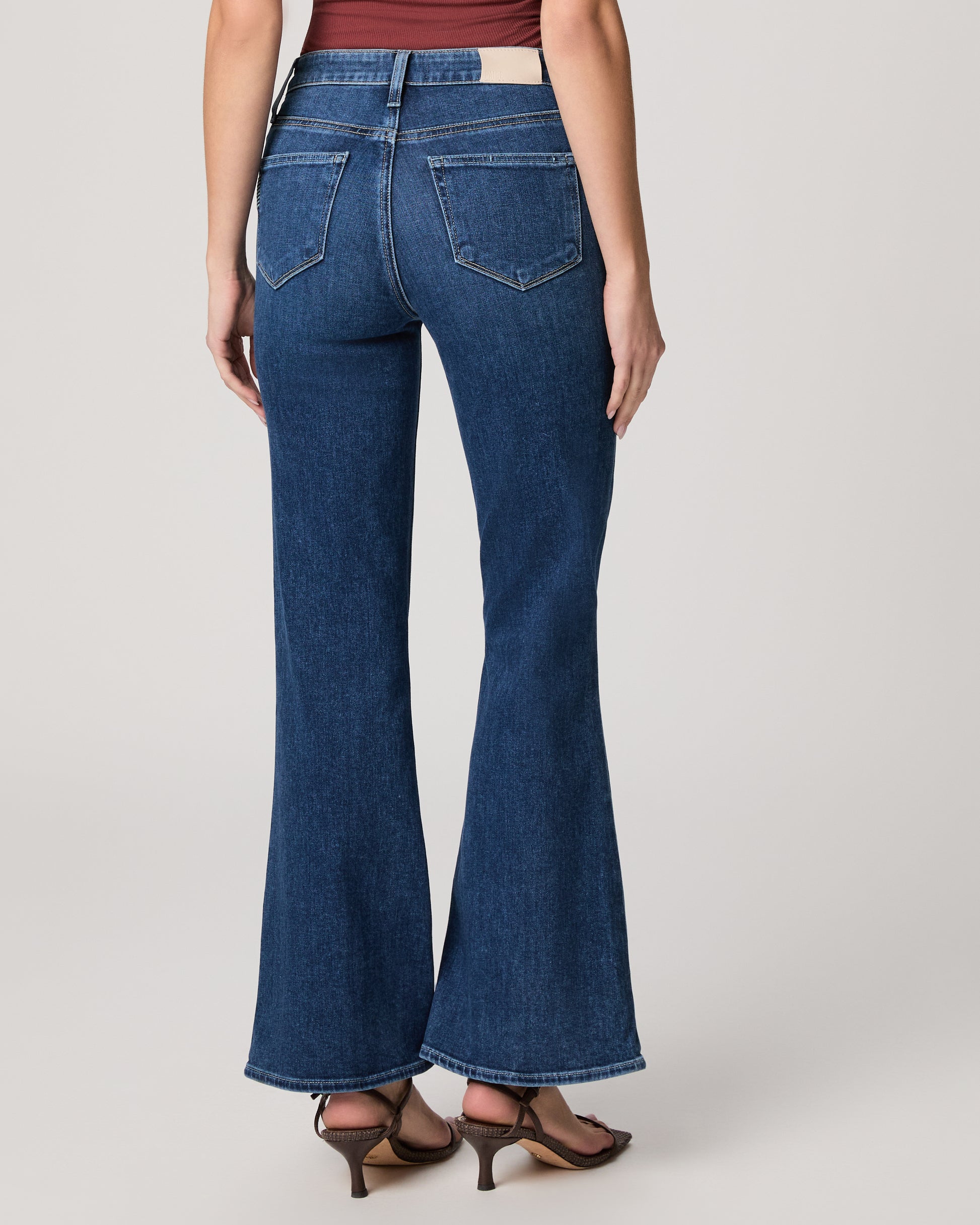 Flared blue jeans worn by a person on a plain background