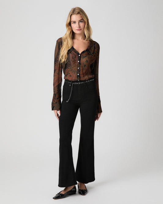 Model standing facing forward, arms at her sides, wearing a sheer brown paisley blouse with bell sleeves, a chain belt, Marlow Skimmer Flare Jeans in Black Shadow, and black pointed flats