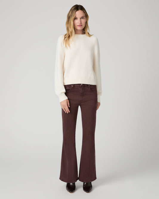 Women wearing a white top paired with burgundy jean and brown boots against a white background