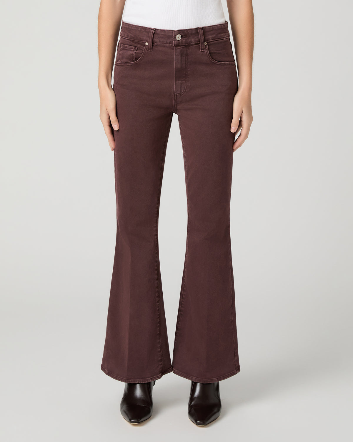 Women wearing a white top paired with burgundy jean and brown boots against a white background