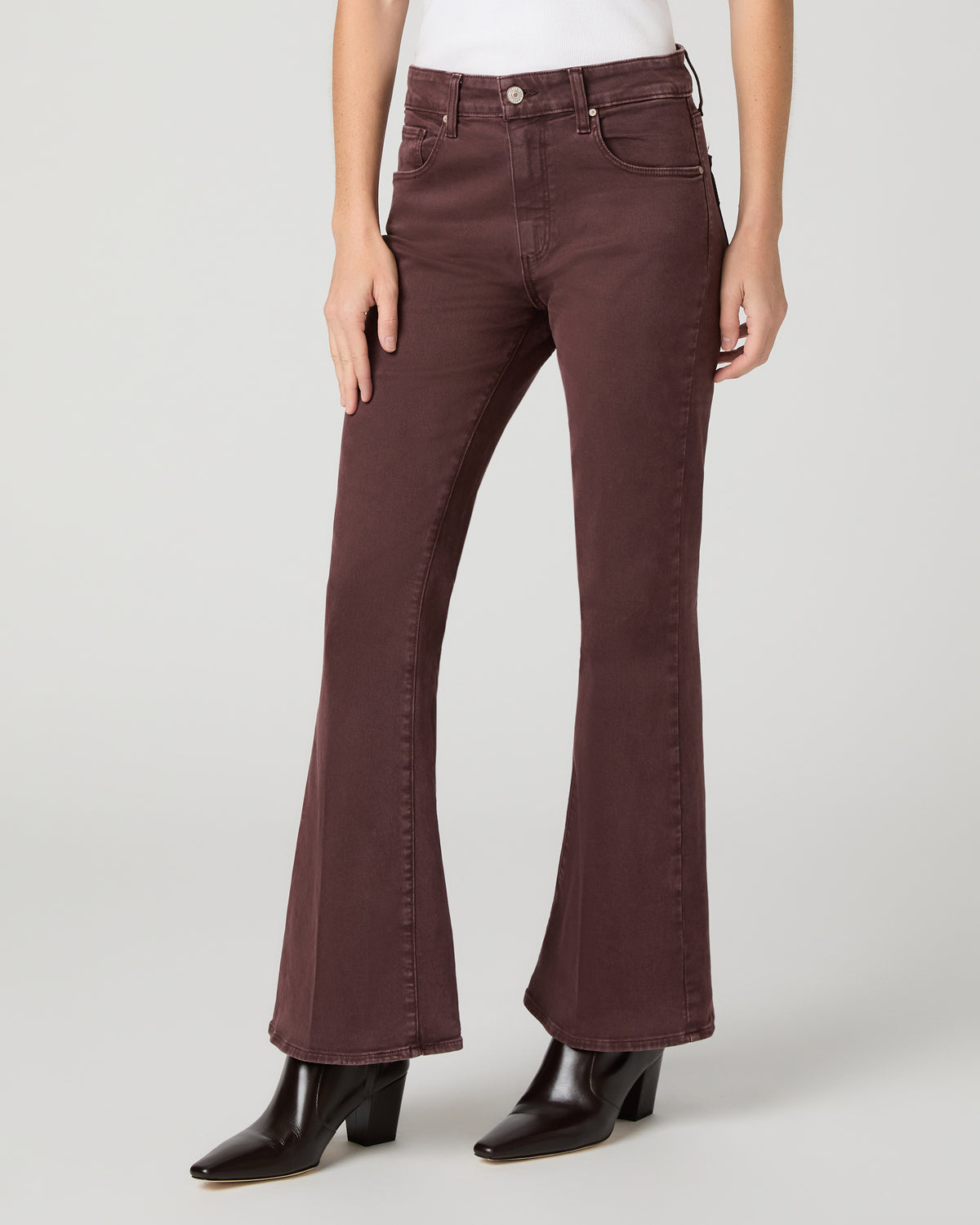 Women wearing a white top paired with burgundy jean and brown boots against a white background