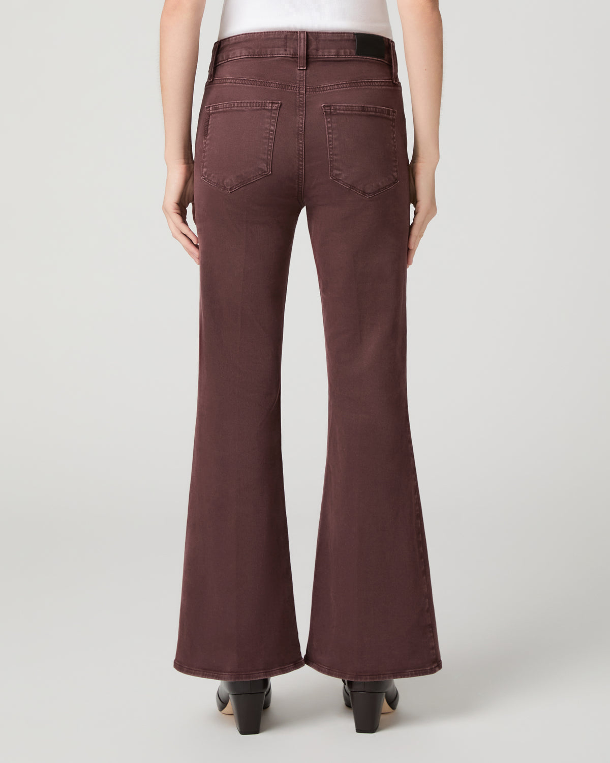 Women wearing a white top paired with burgundy jean and brown boots against a white background