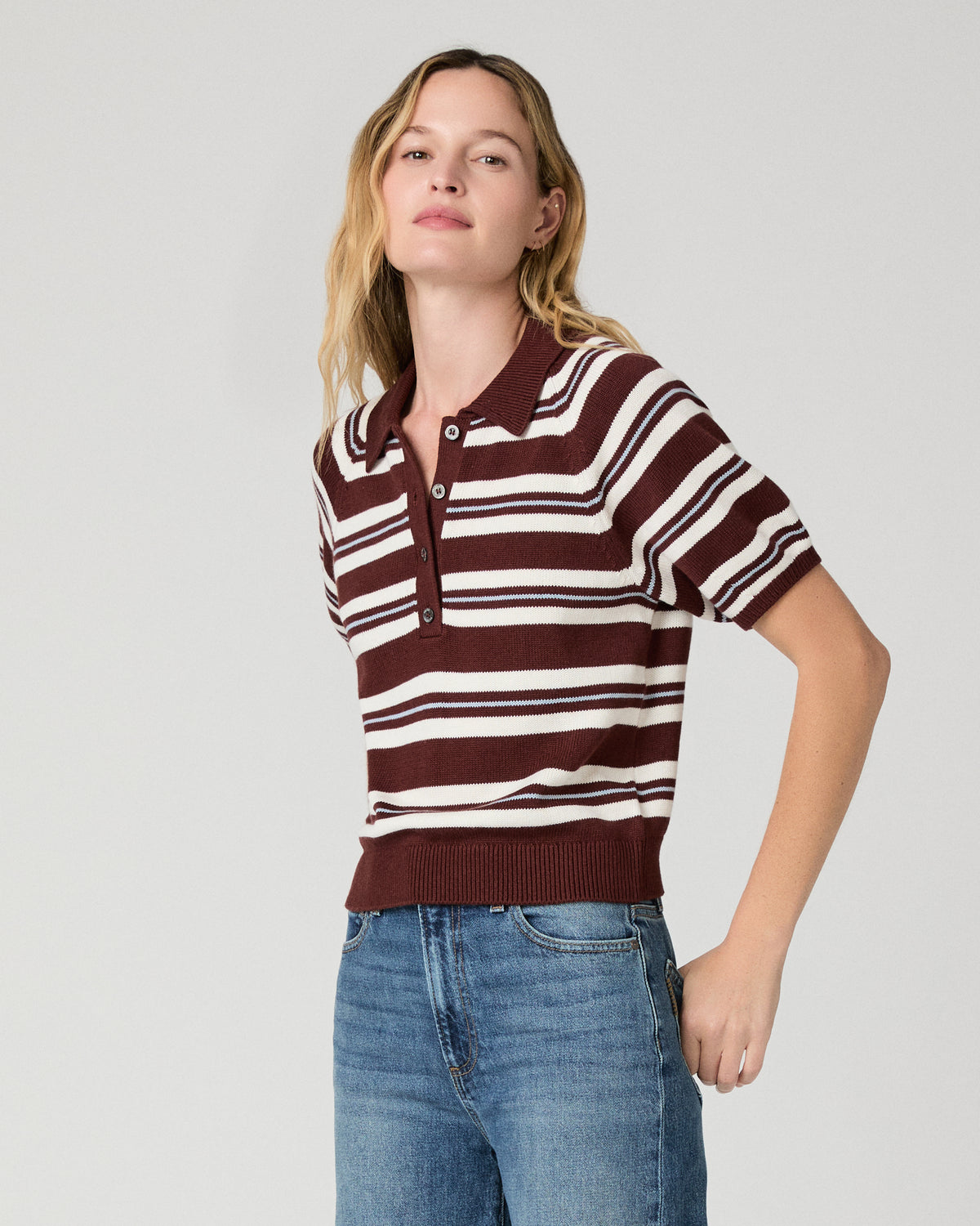 Women wearing a white and brown stripe top and blue jeans against a white background