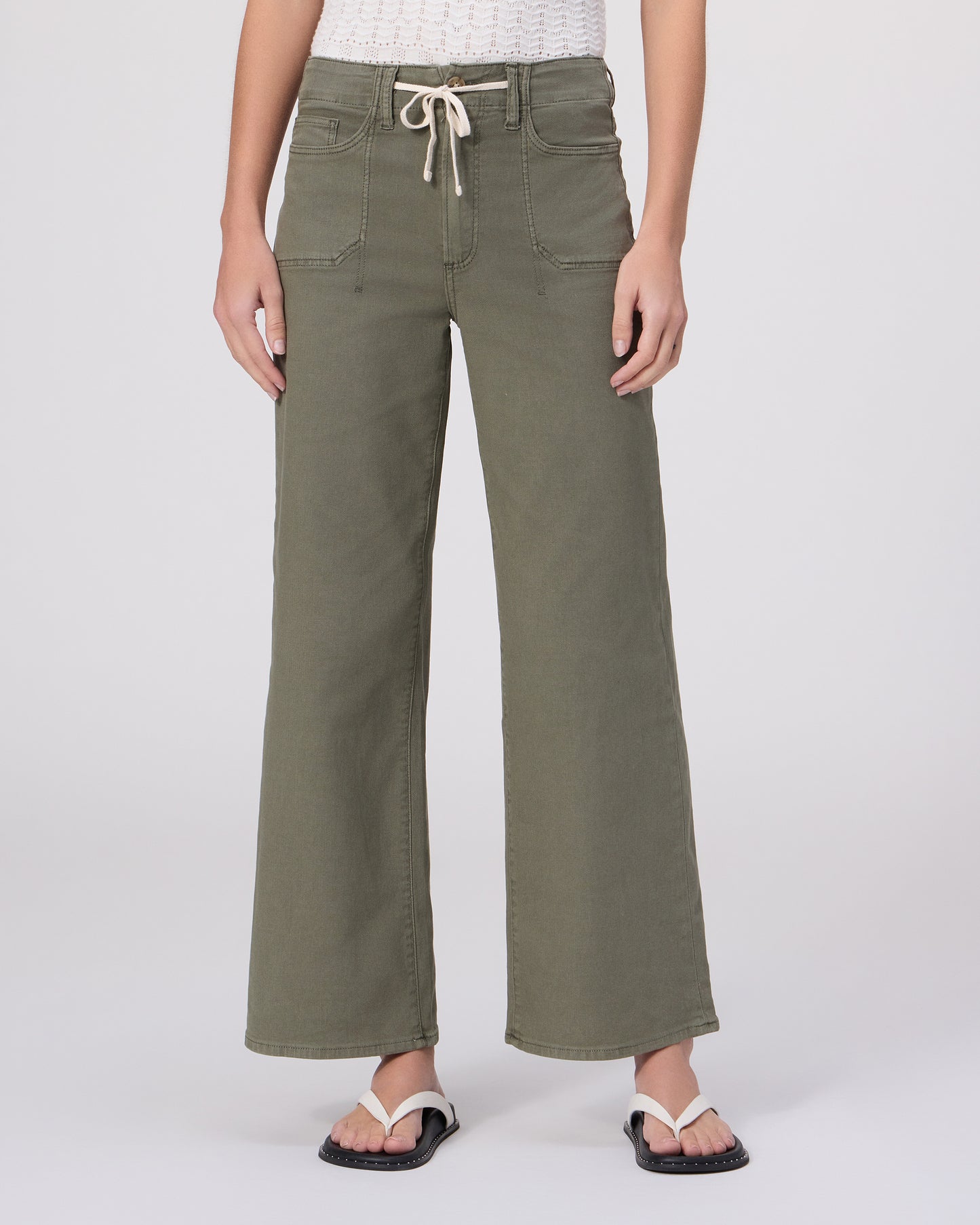 Woman wearing a white top and green pants on a white background