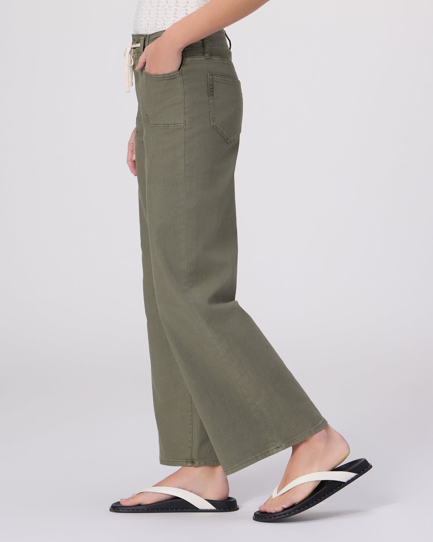 Woman wearing a white top and green pants on a white background