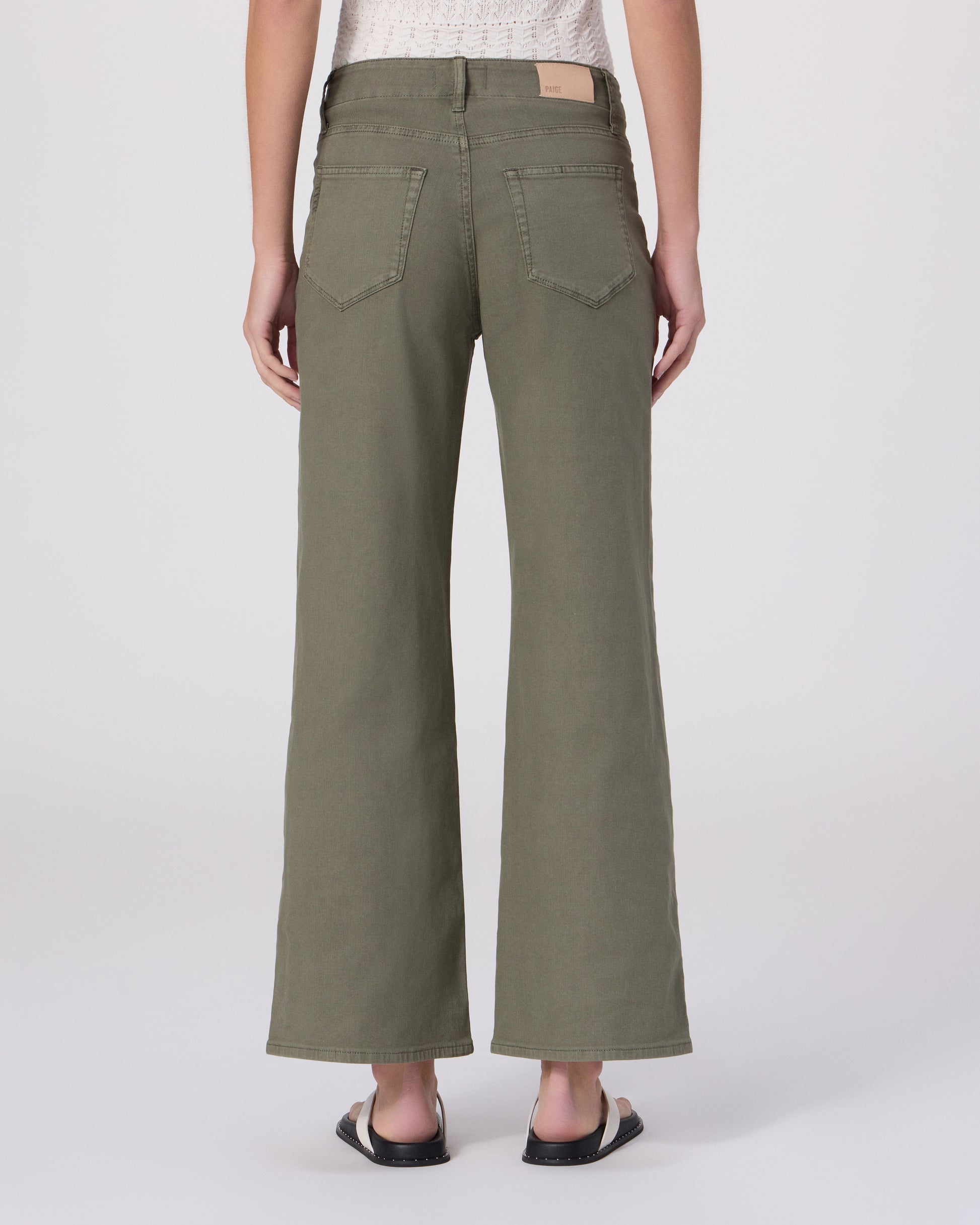 Woman wearing a white top and green pants on a white background