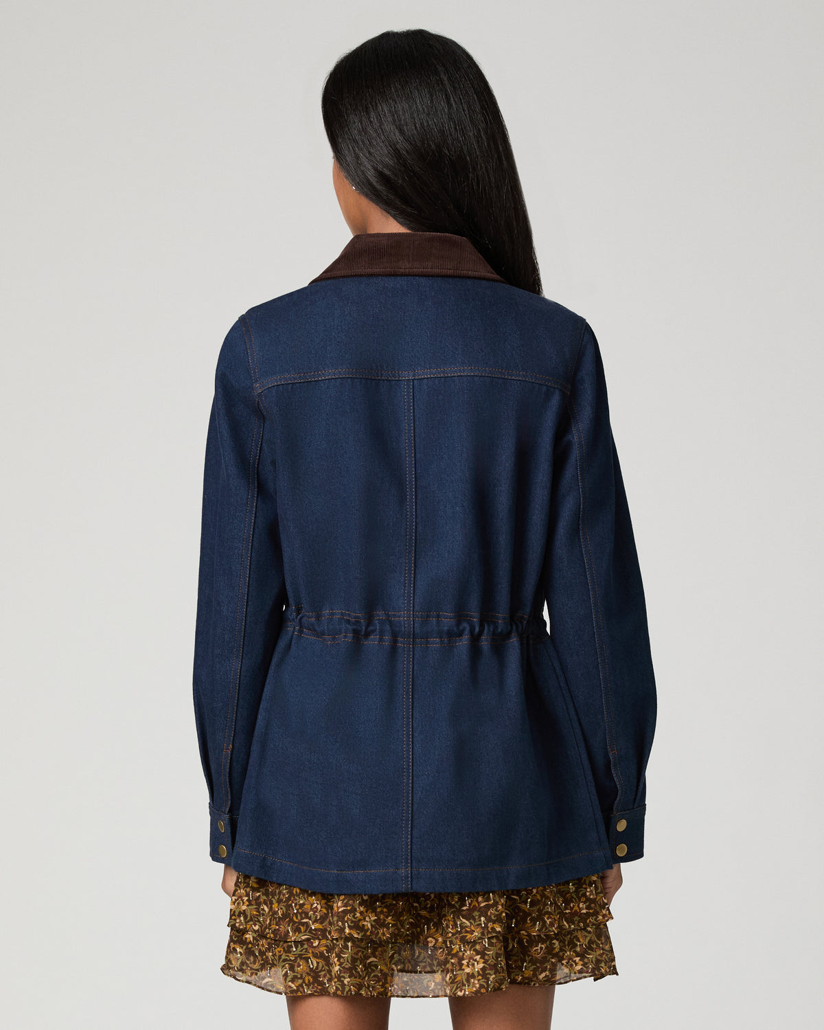 Back view close-up of a dark denim barn jacket showing the back yoke seaming and cinched waist tab detail.