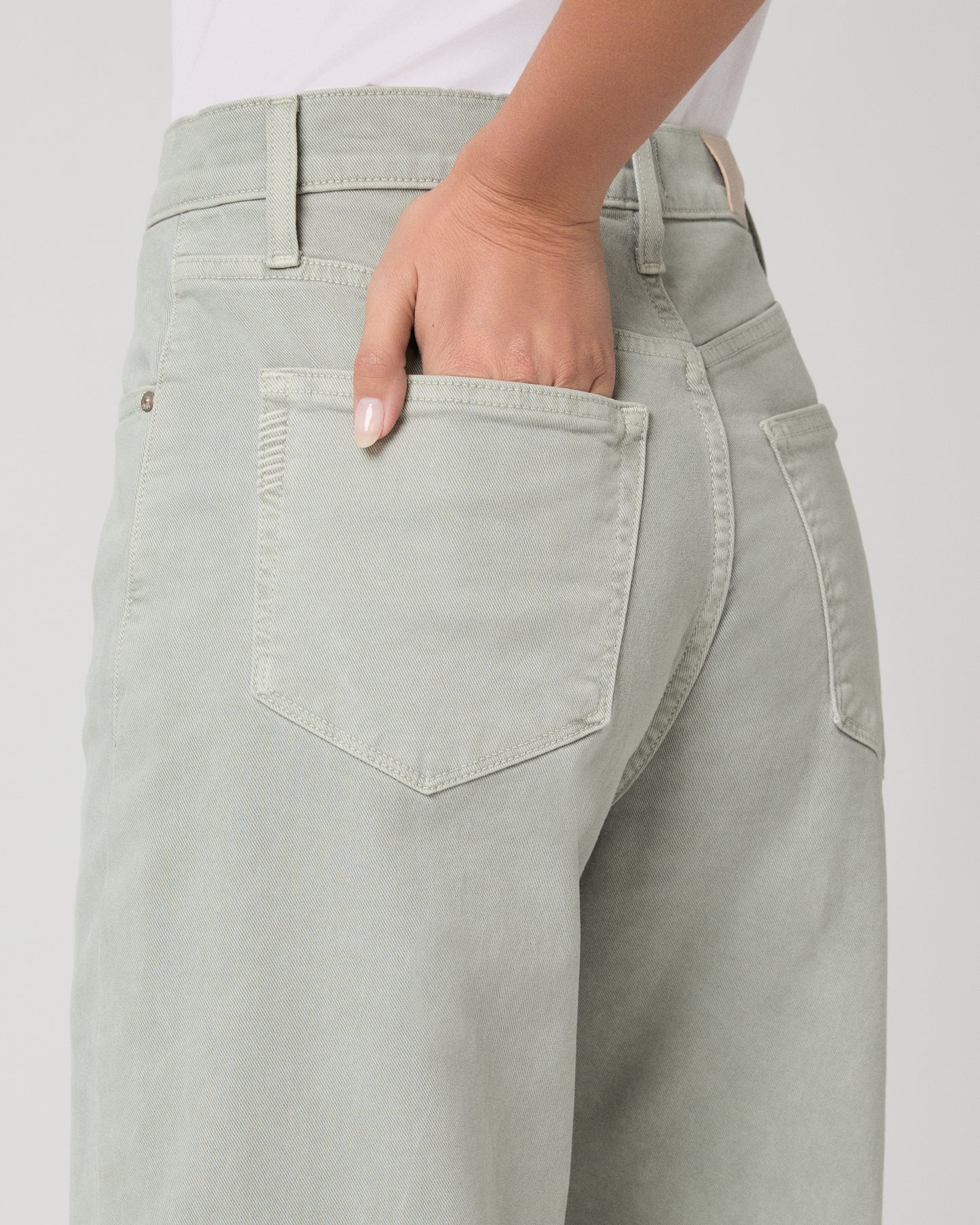 Woman wearing a white t-shirt and light green pants on a white background