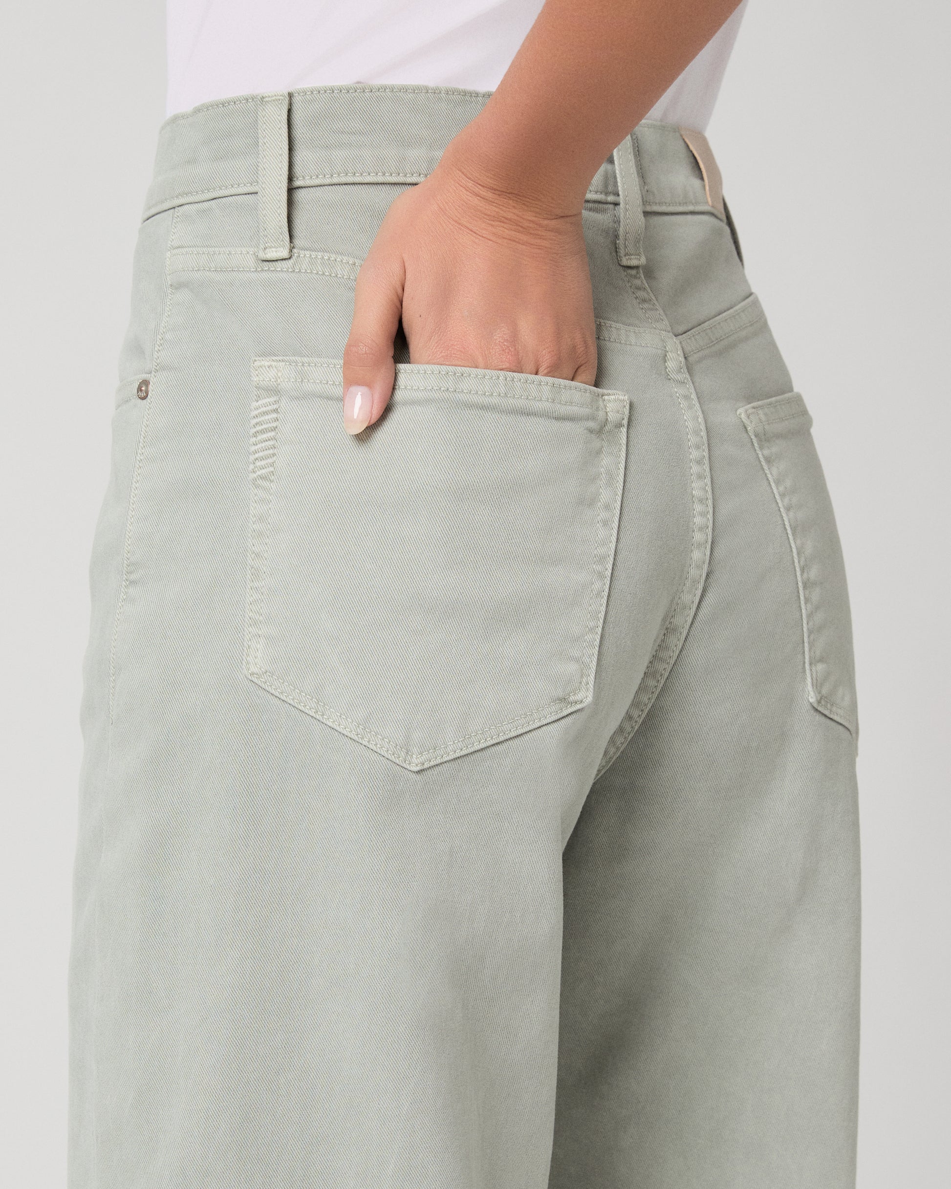 Woman wearing a white t-shirt and light green pants on a white background