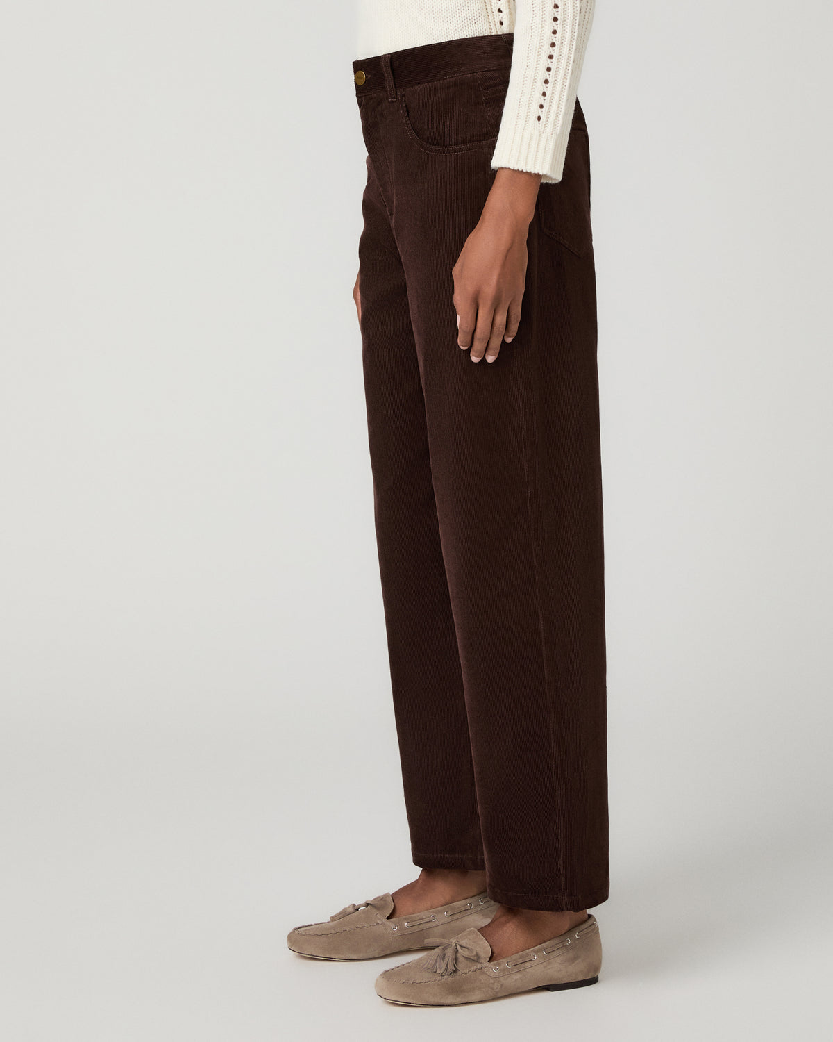 Women wearing a ivory long sleeve sweater paired with corduroy brown pant and grey flats against a white background