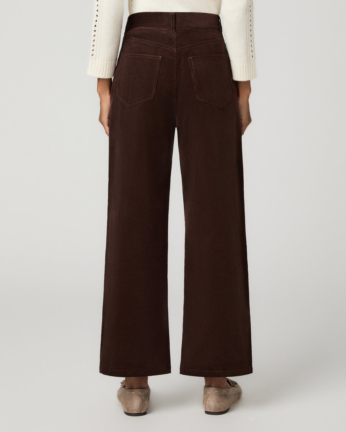 Women wearing a ivory long sleeve sweater paired with corduroy brown pant and grey flats against a white background